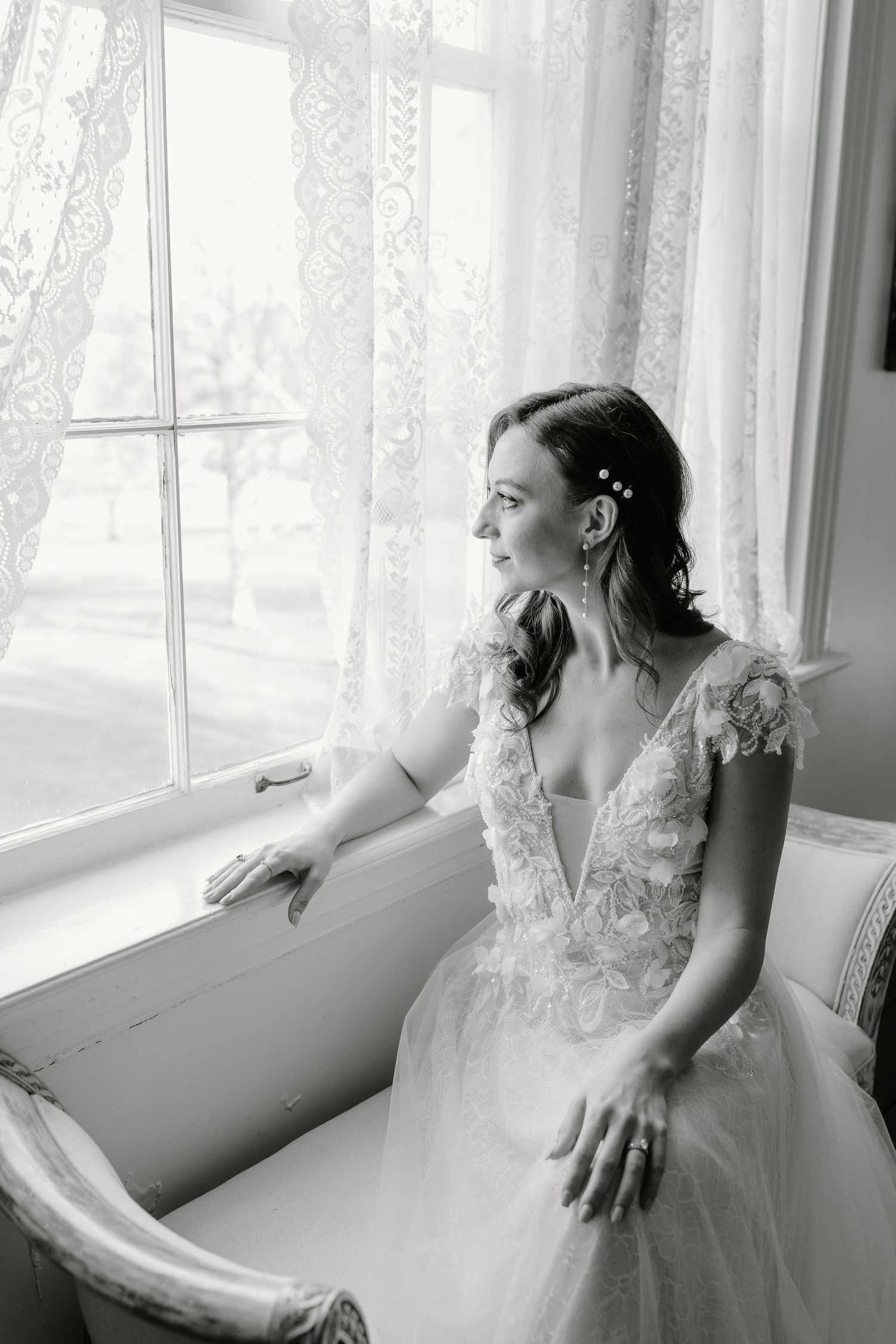 A series of black and white photos showing a bride in a lace gown reclining near a window in dreamy poses.