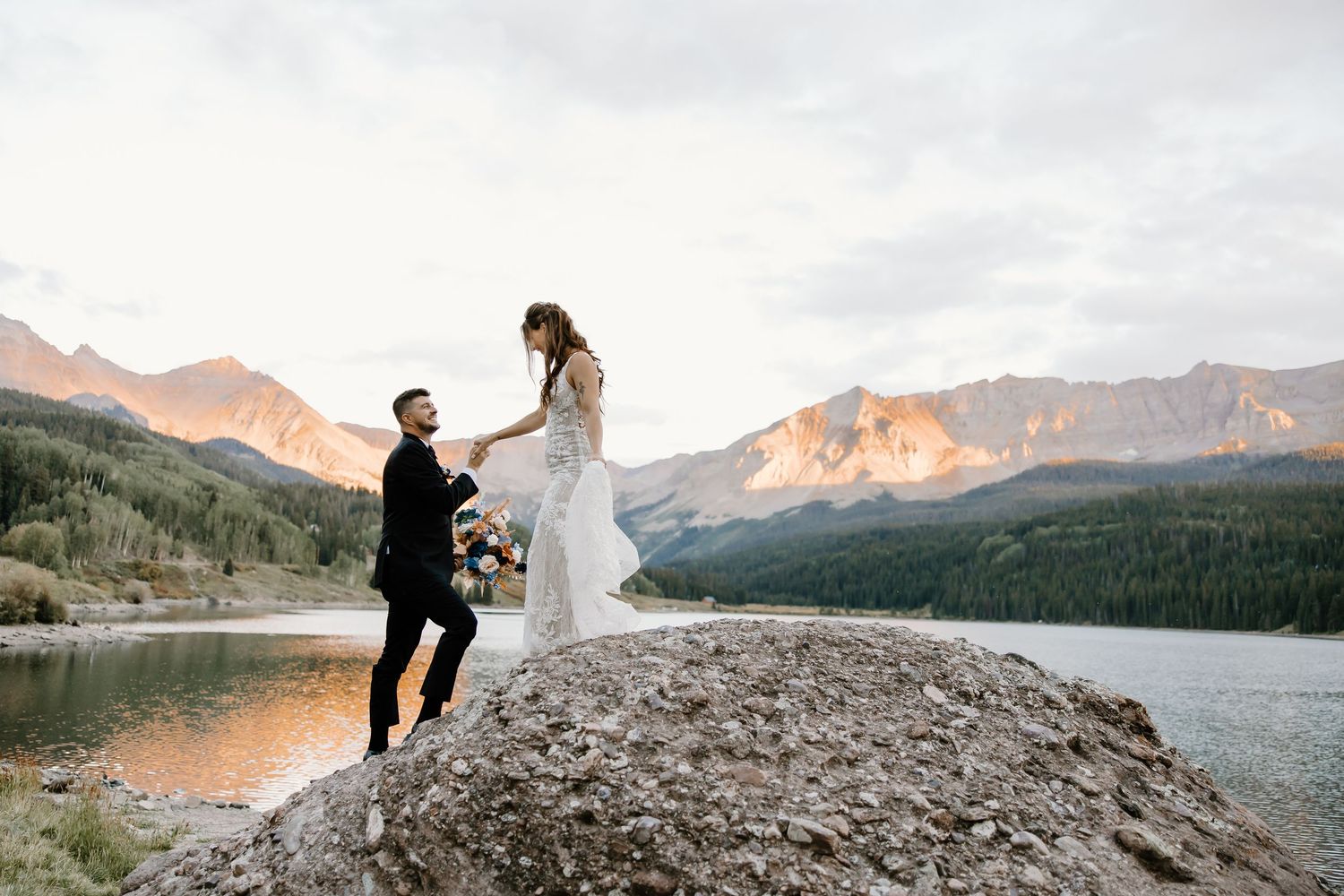 Couple celebrating their wedding day on a rocky overlook with stunning mountain scenery.