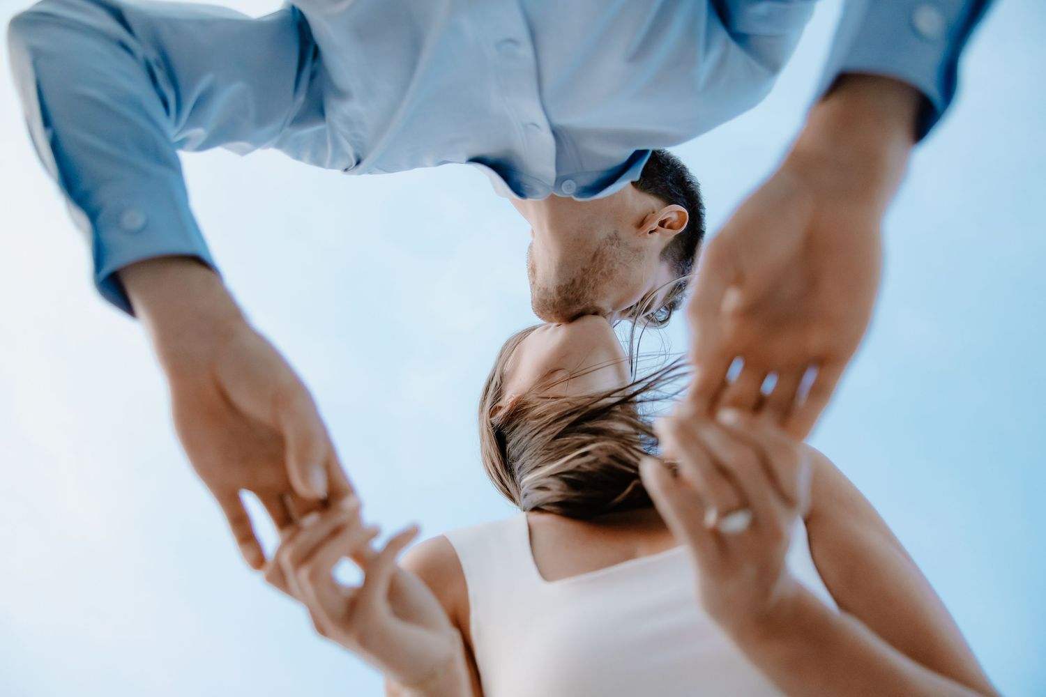 Multiple hands reaching towards blue sky in circular formation.