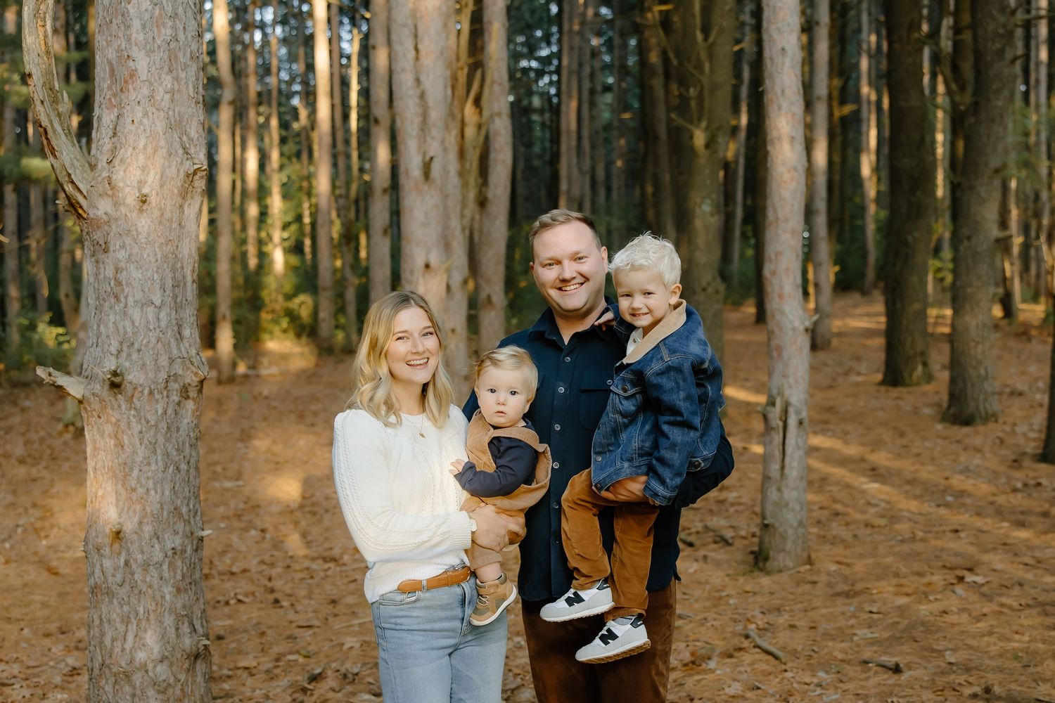 Natural candid family portraits taken among tall pine trees.