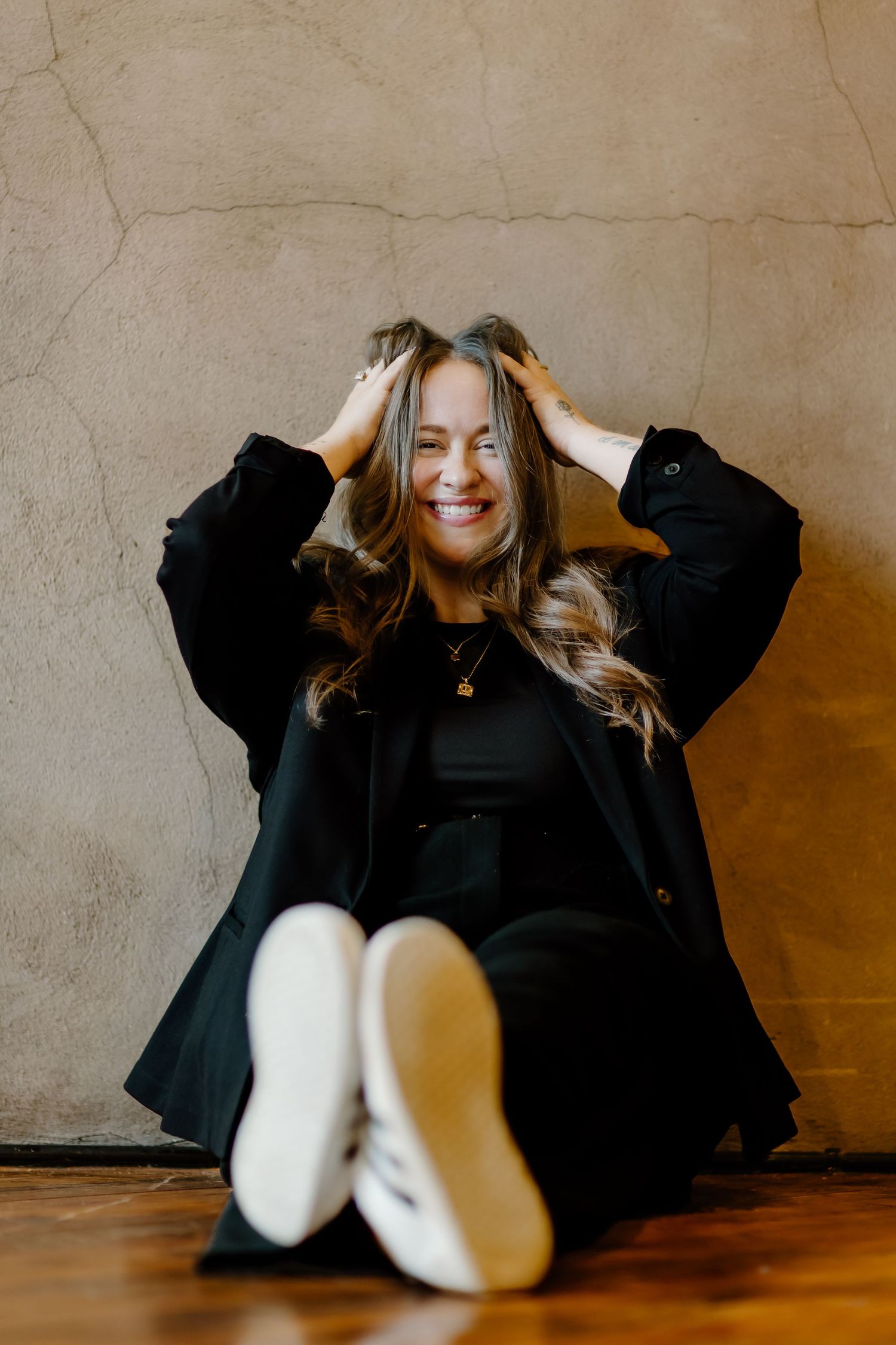 Person in black clothing lying on wooden floor with joyful expression.