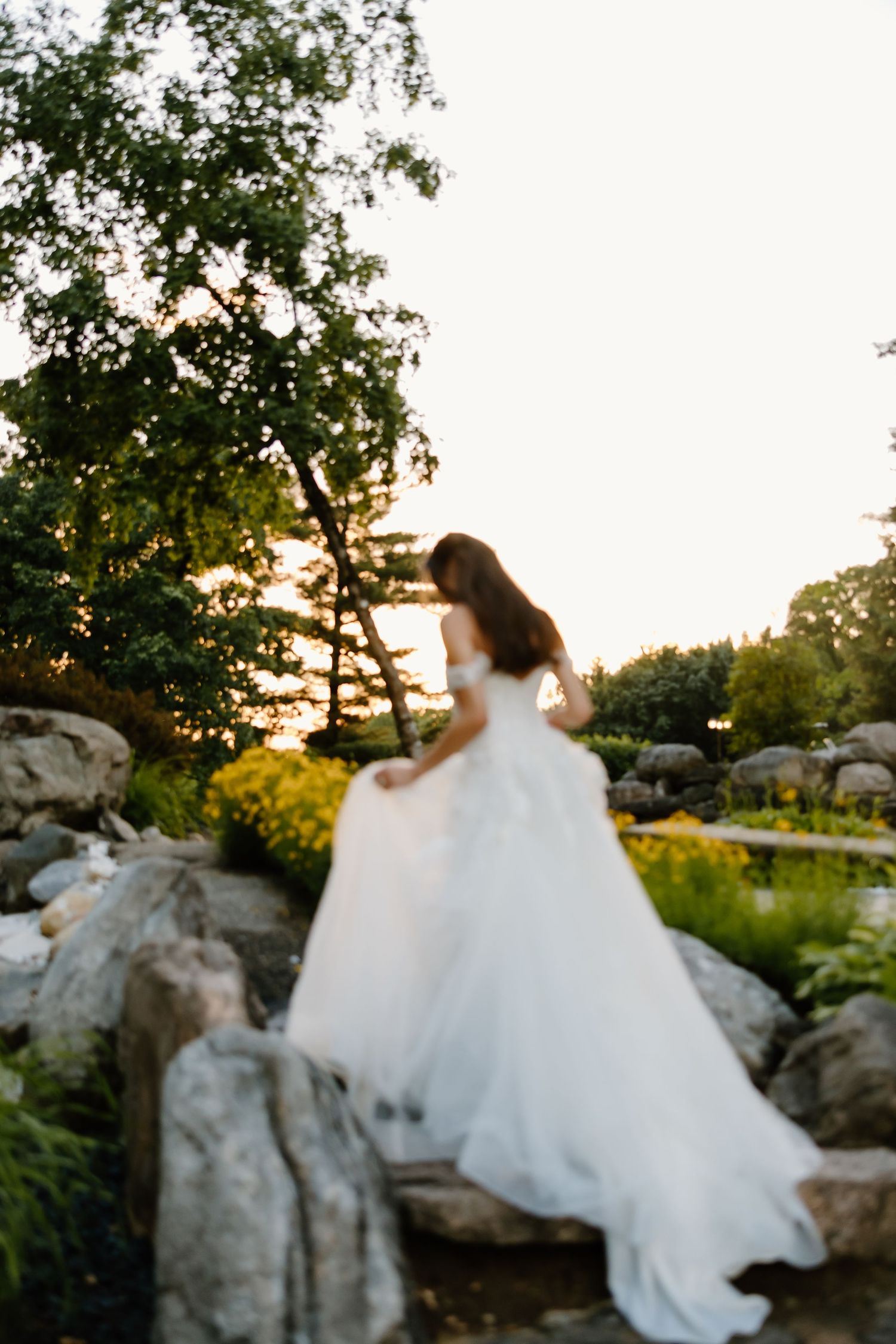 Wedding dress silhouette against sunset sky with rocky landscape.