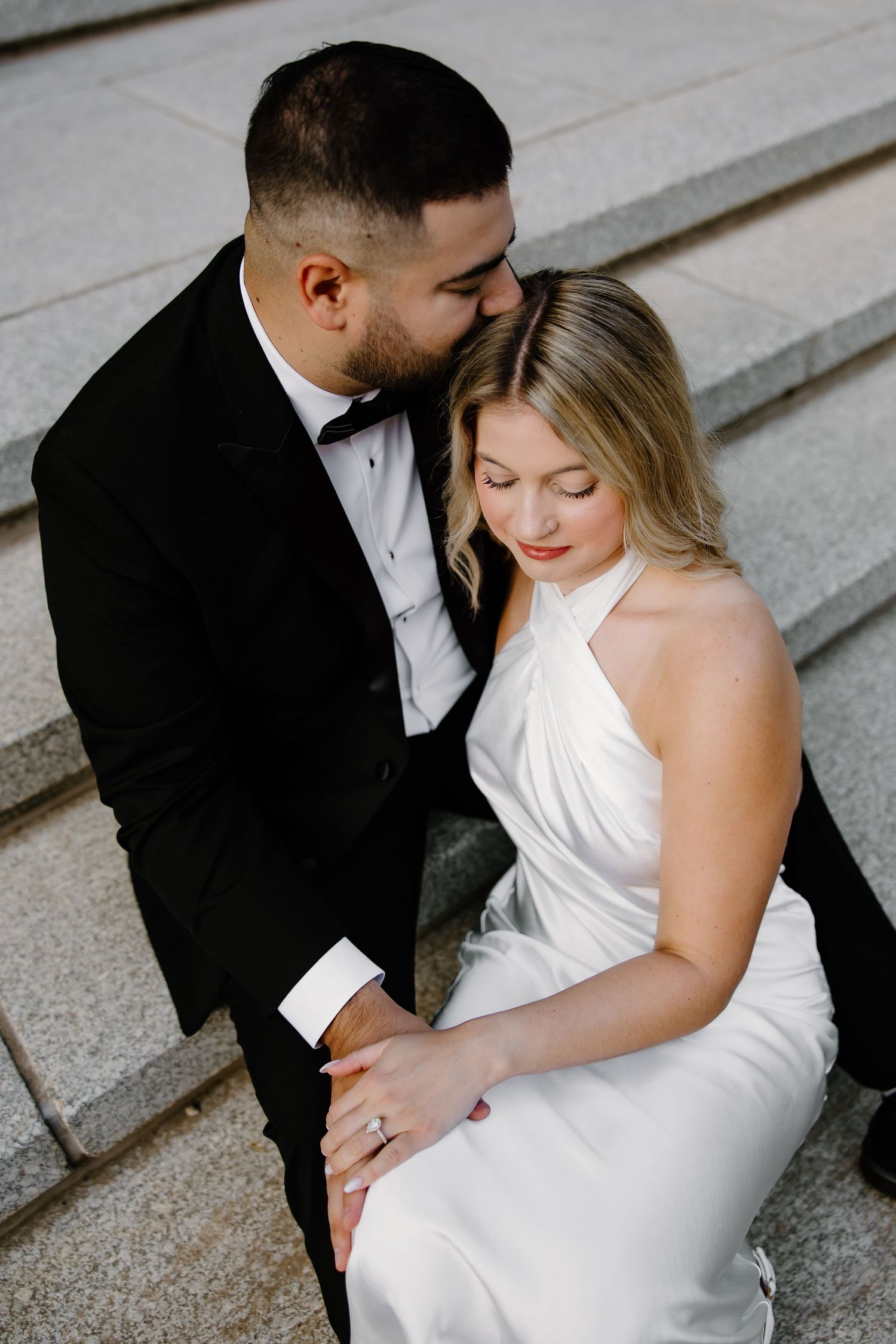 Elegant bride and groom pose on stone staircase in black and white.