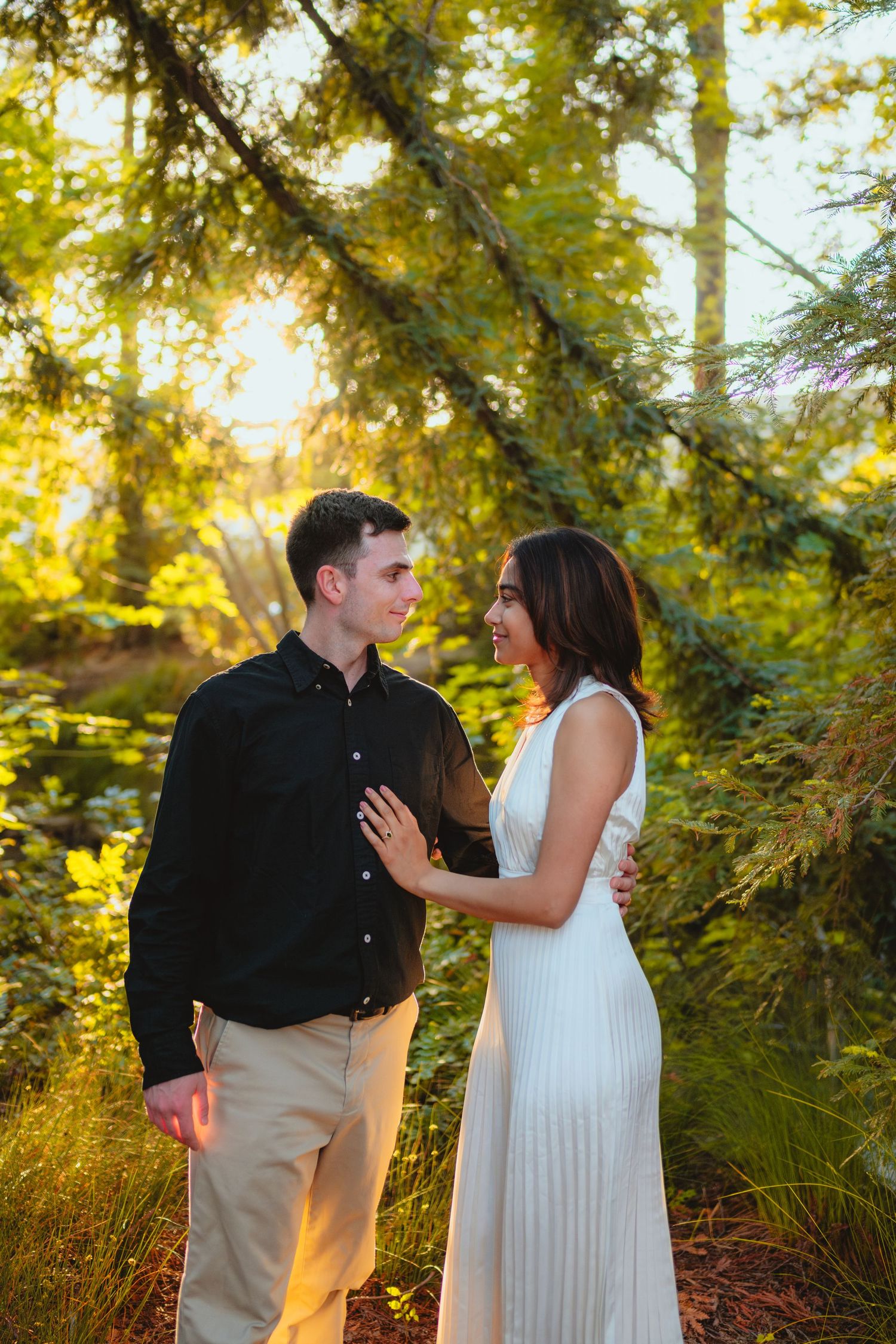 Romantic couple portraits in a forest during golden hour showing joyful interactions.