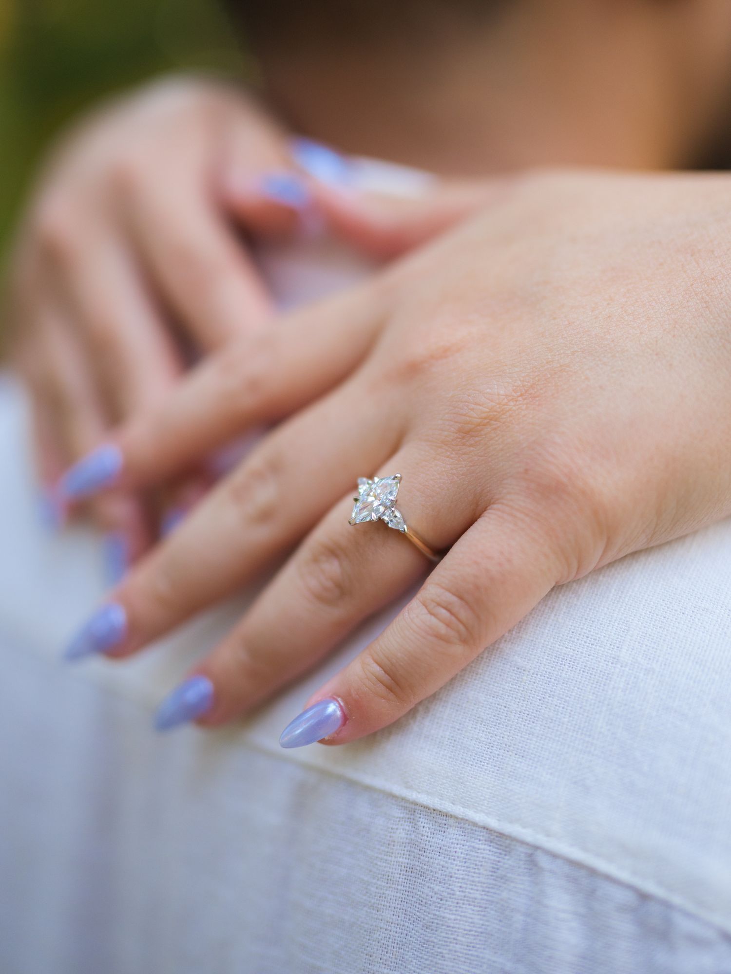 Close-up of a sparkling diamond engagement ring on a woman's hand with pastel manicure.