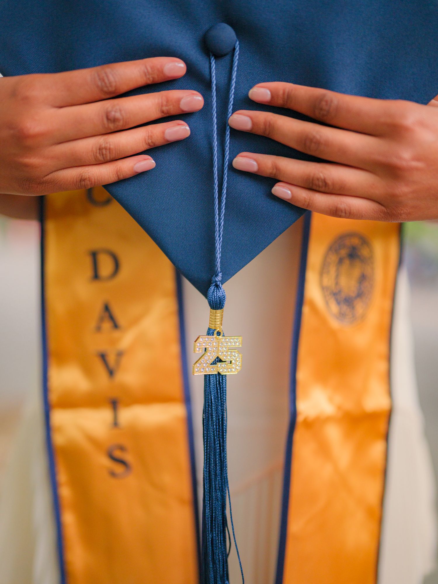 Hands arranging blue graduation caps with gold tassels in sequence.