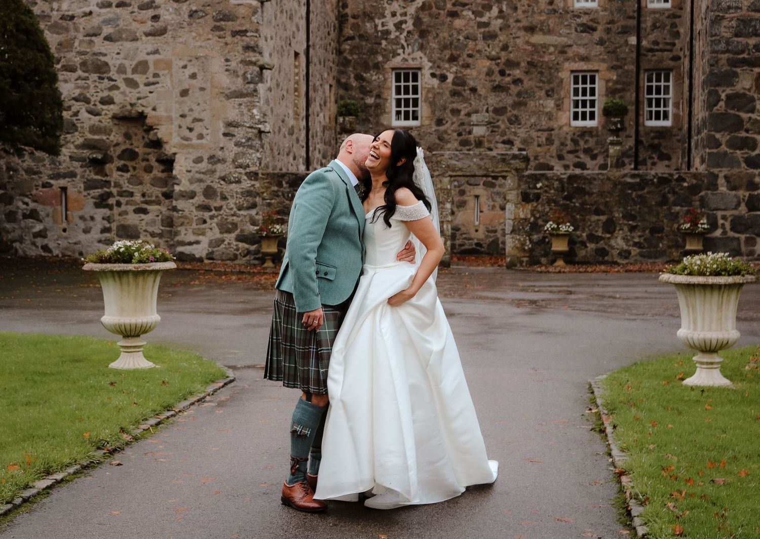 A romantic wedding moment captured in front of a rustic stone wall at an elegant venue.