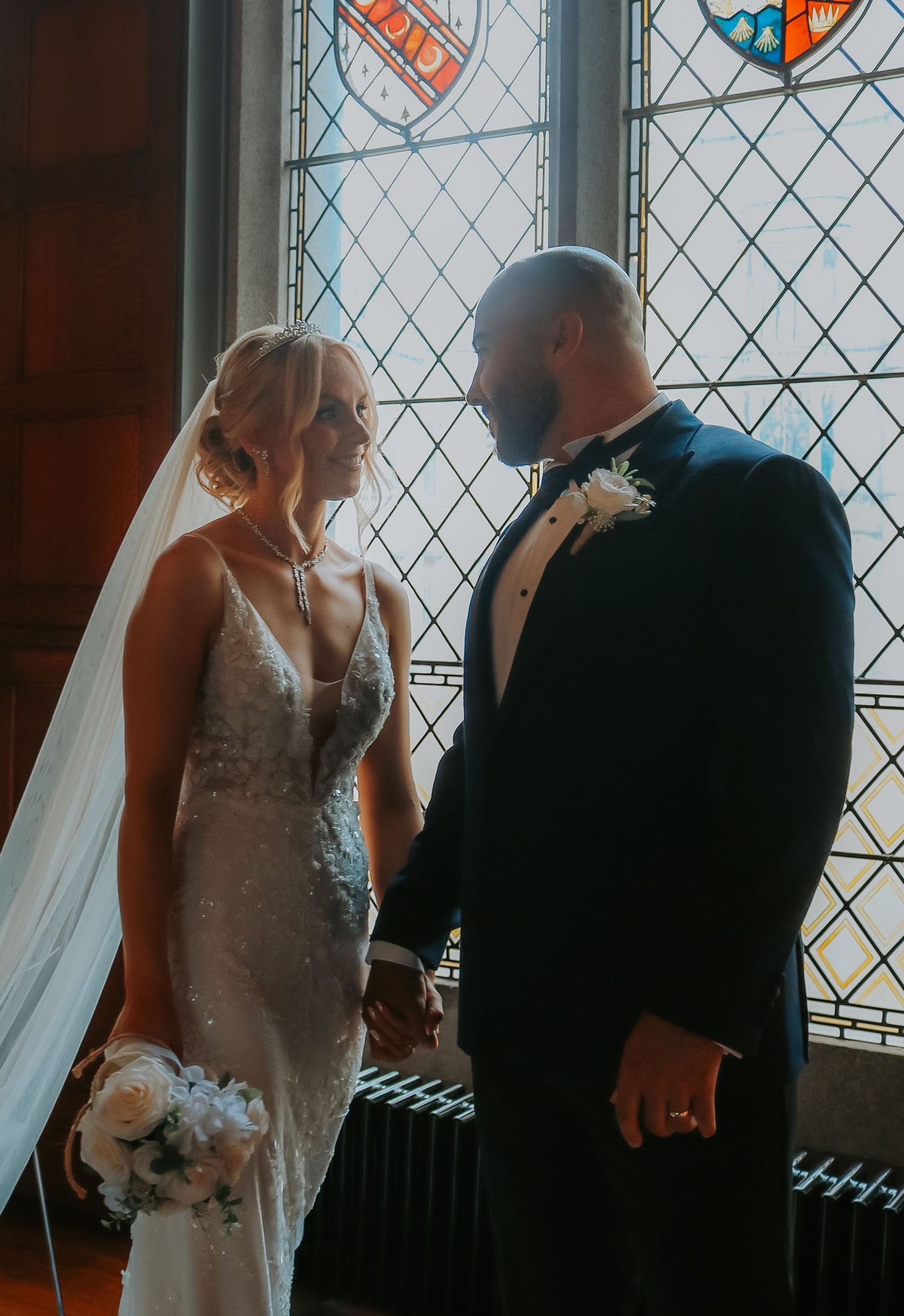 A bride and groom share an intimate moment by a stained glass window in a series of romantic wedding photos.