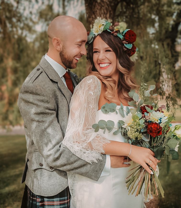 A romantic wedding couple shares candid moments in an outdoor setting with natural lighting and rustic fall decor.