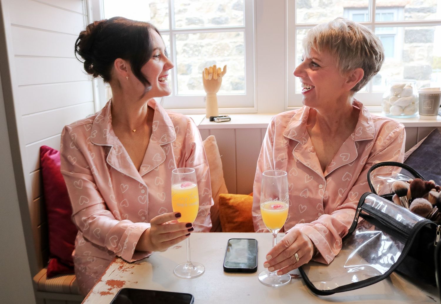 Two people having an animated conversation over drinks and documents at a bright cafe table.