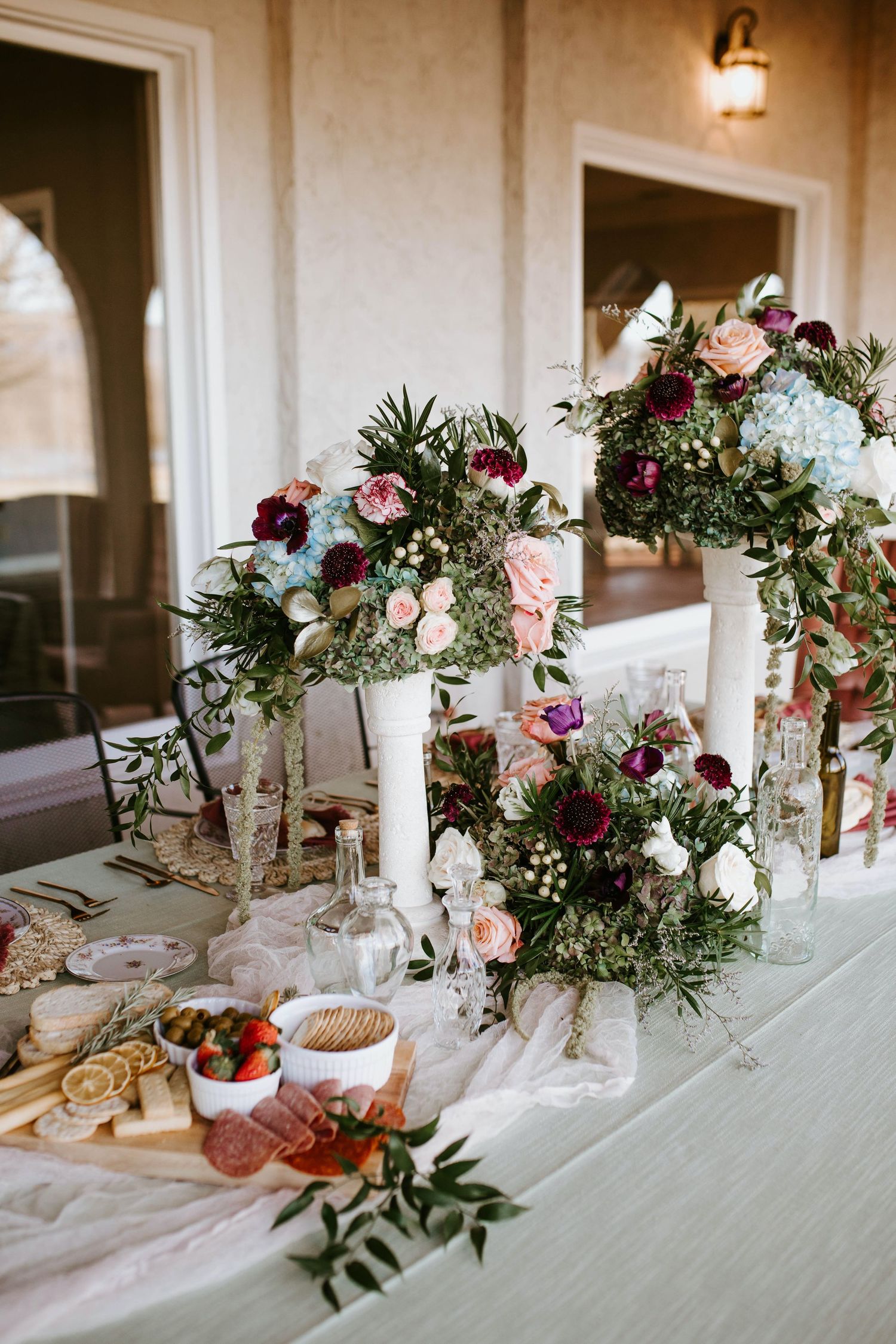 Elegant Aberdeen wedding reception table settings with burgundy and pink floral centerpieces and white candles on linen tablecloths.