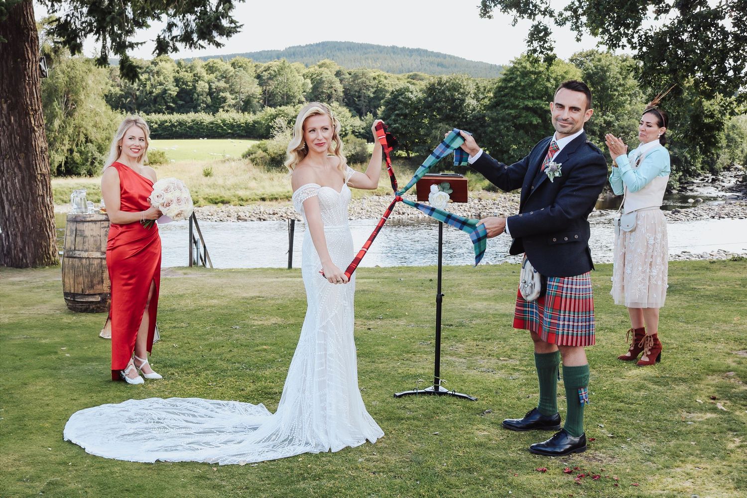 A couple celebrates their outdoor wedding ceremony in a scenic garden setting with guests watching from a distance.