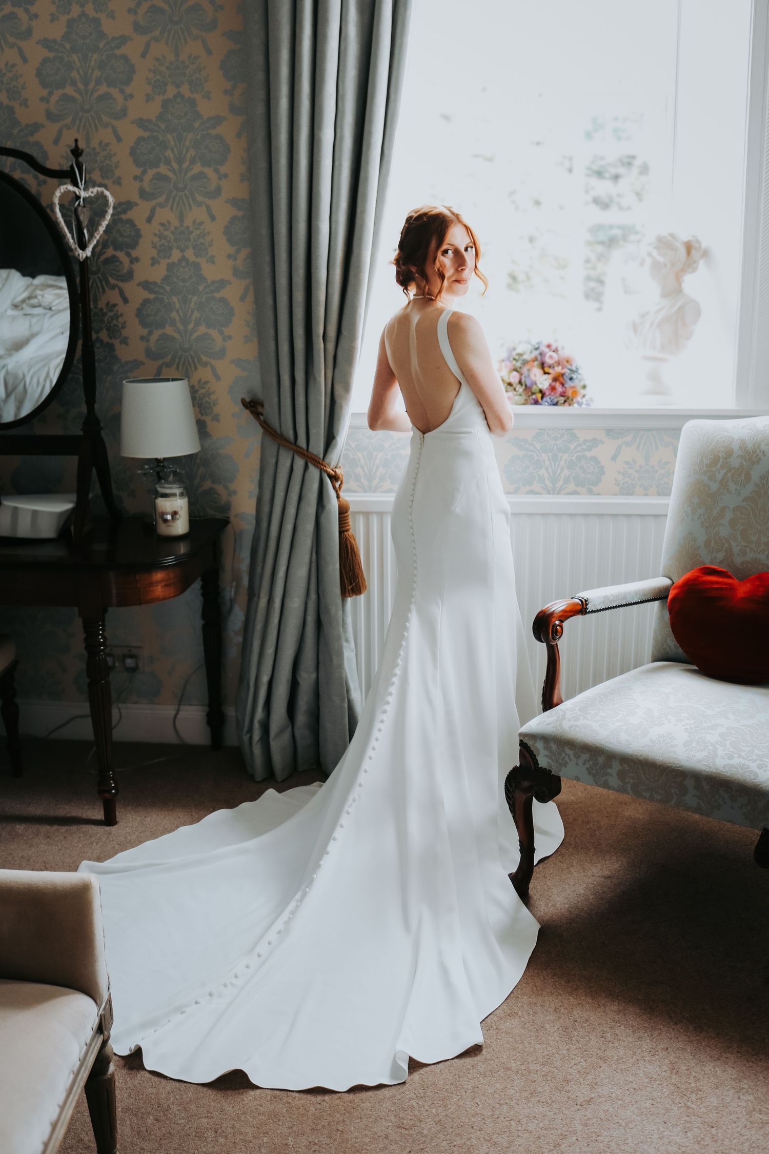 A bride in an elegant white wedding gown is photographed from multiple angles in a room with damask wallpaper and curtains.
