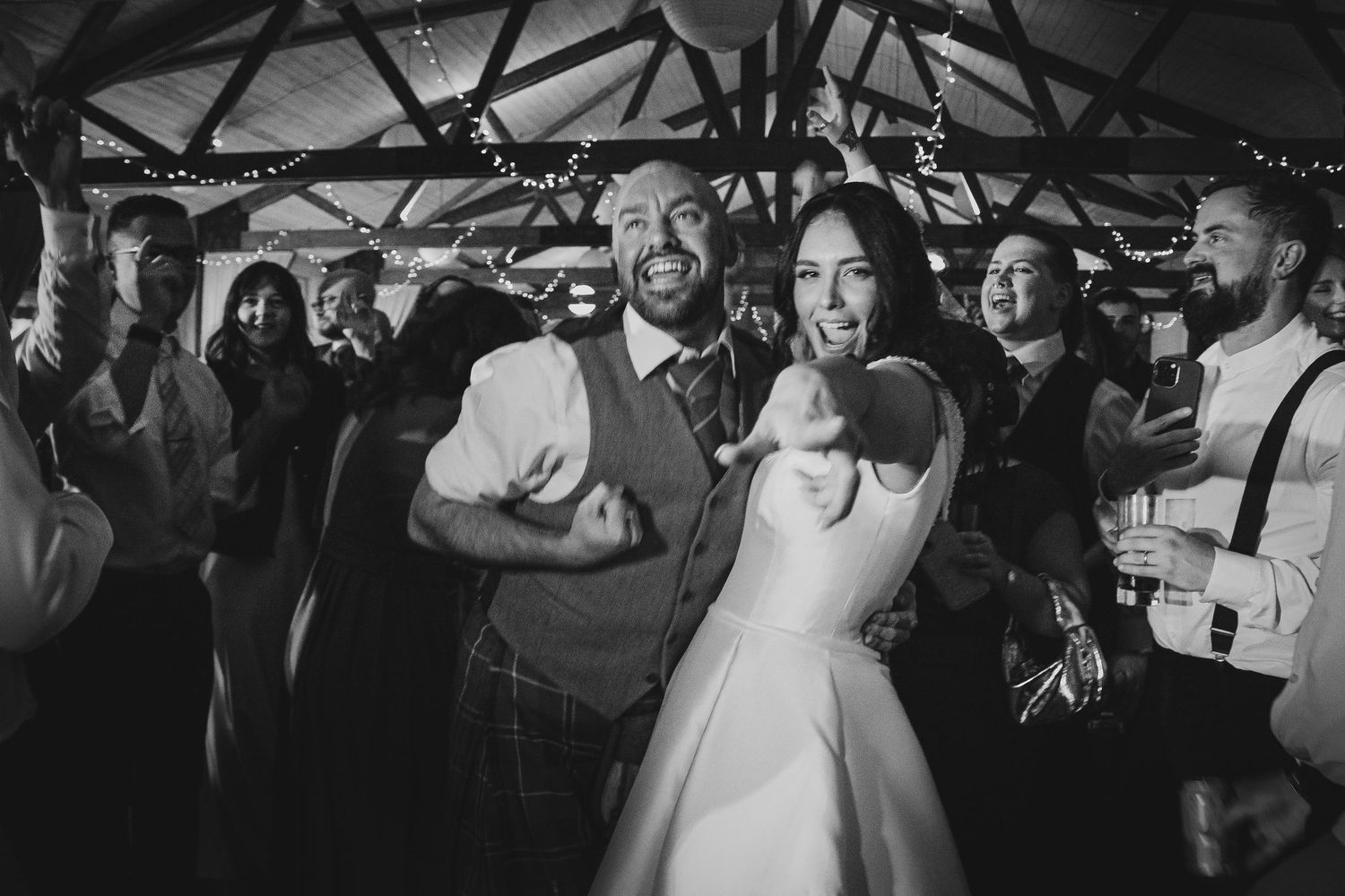 Black and white photo series of a couple dancing together at a wedding reception surrounded by guests.