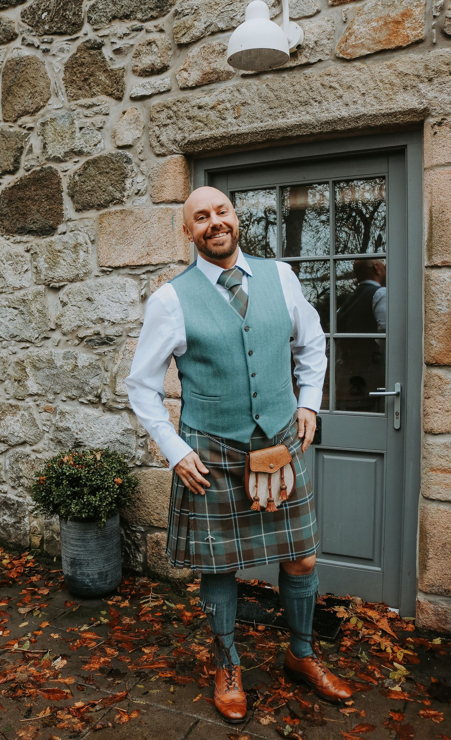 A series of photos showing traditional Scottish attire with a teal vest and plaid kilt against a rustic stone wall.
