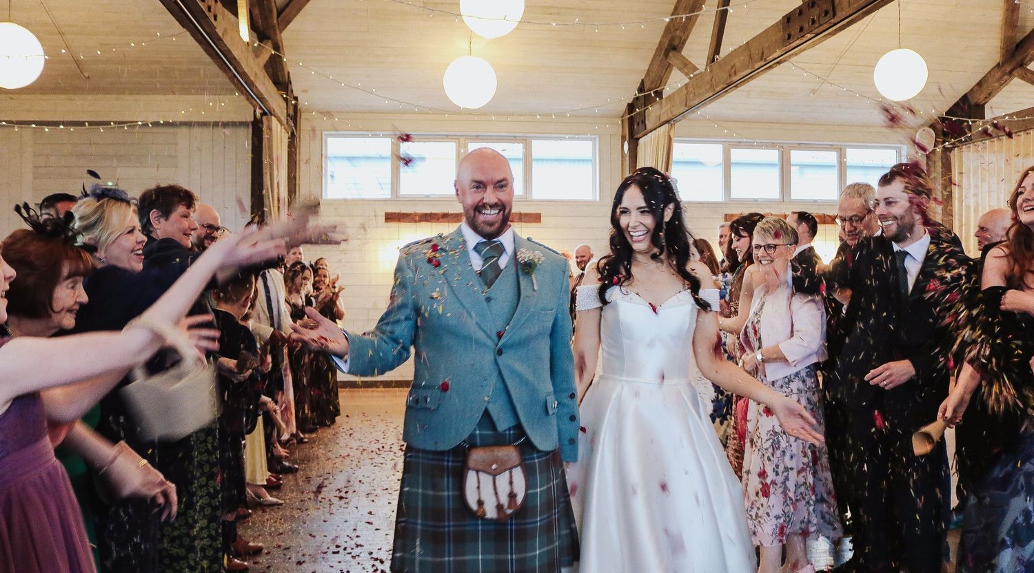Wedding guests dance and celebrate on a rustic wooden dance floor during an evening reception.