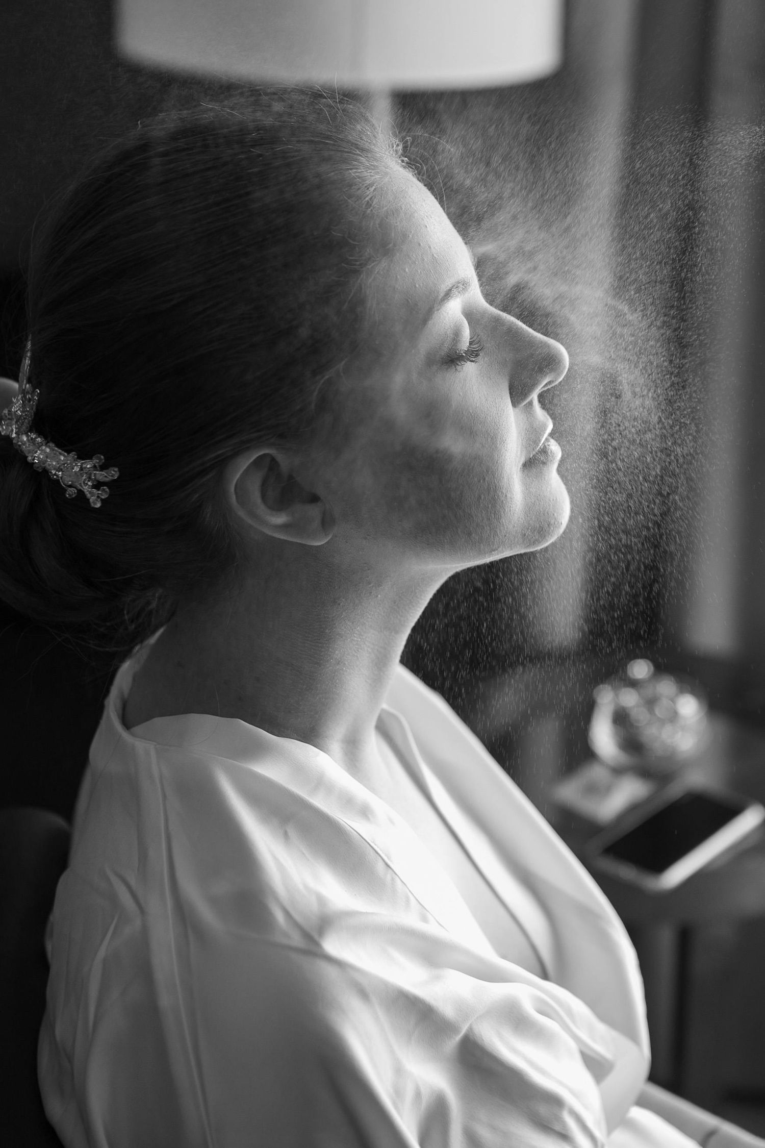 Black and white profile portrait with mist spray and soft lighting creating an ethereal atmosphere.