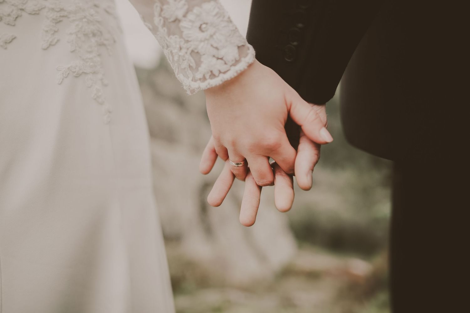 Close-up of hands exchanging rings during an intimate outdoor wedding ceremony.