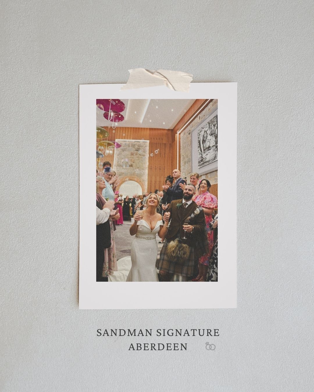 Wedding celebration photos displayed on a light gray wall with text reading 'Sandman Signature Aberdeen' underneath.