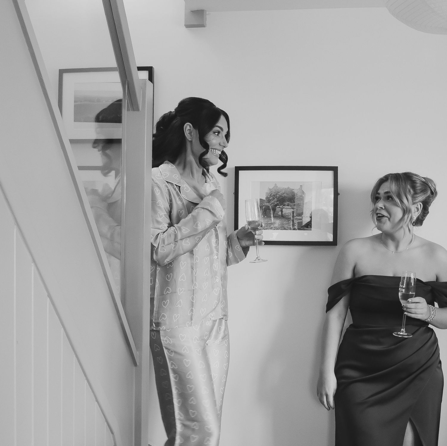 Two people sharing a candid moment and laughing together in a black and white photograph on a staircase.