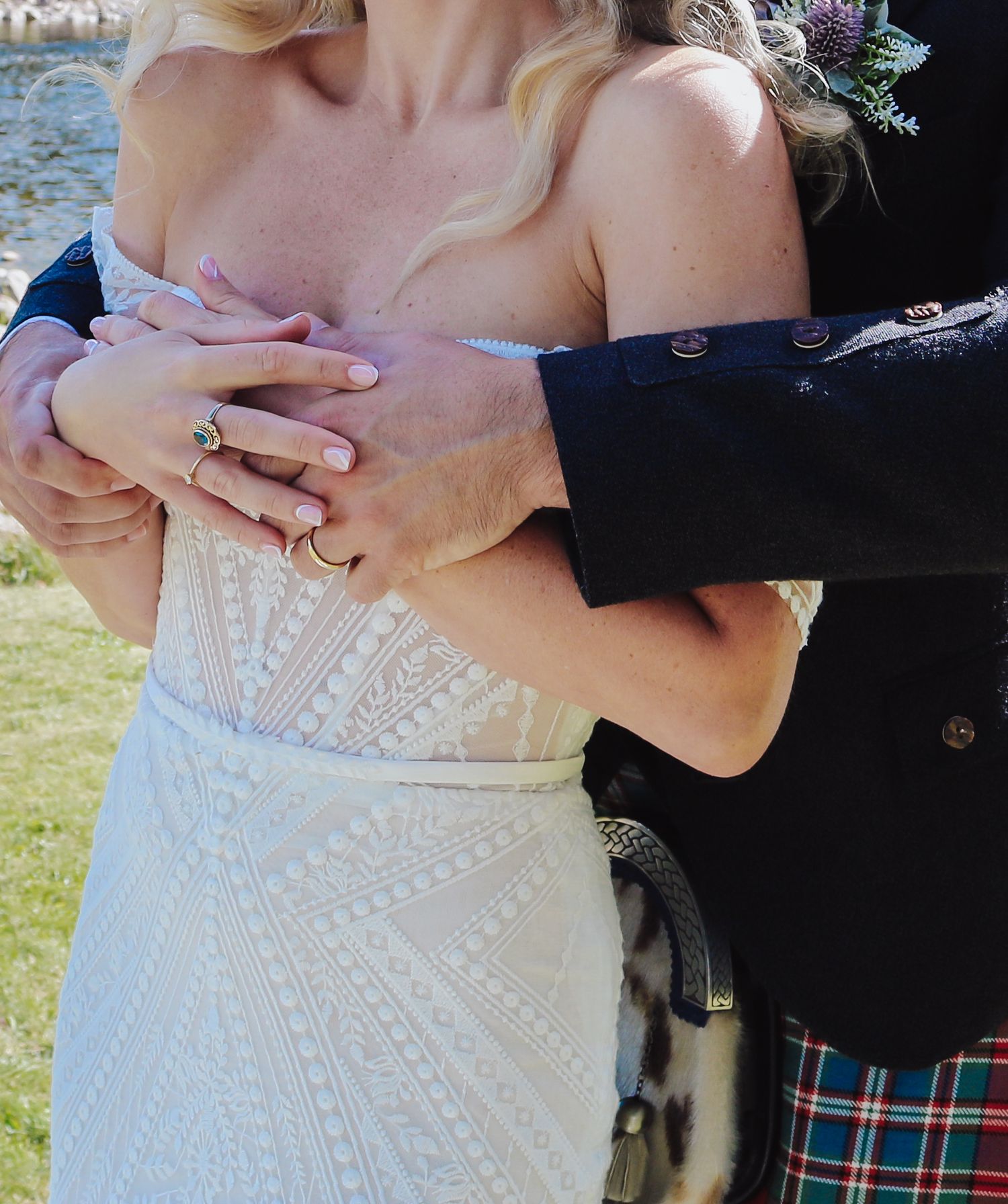 A person in a white beaded wedding dress poses with someone wearing traditional Scottish kilt attire.