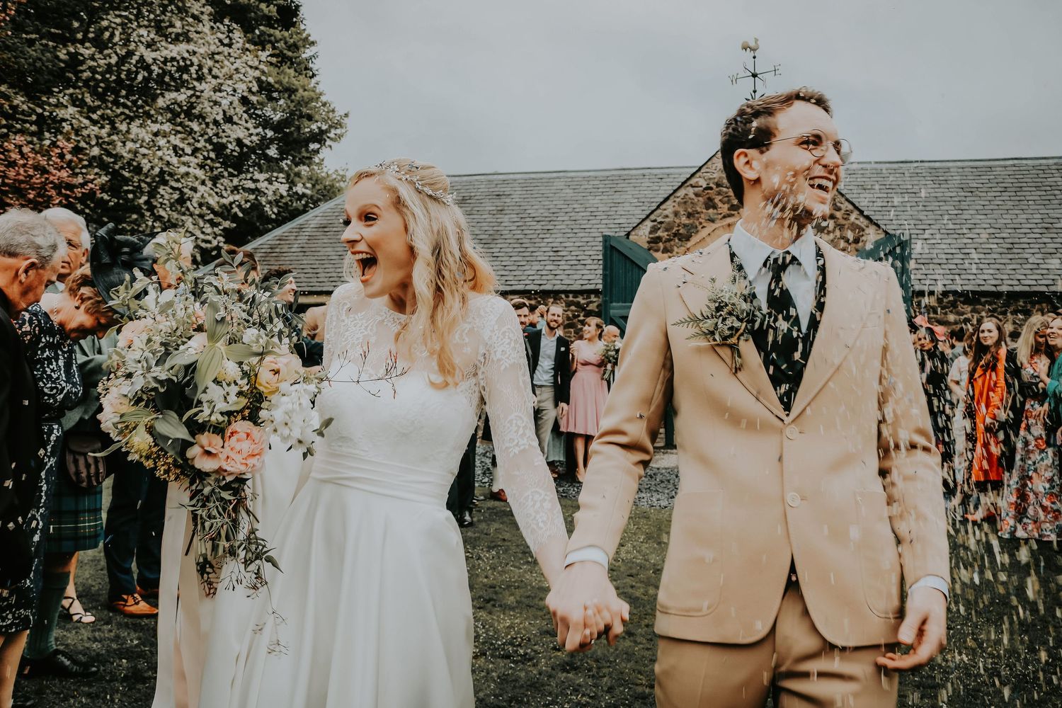 Couple shares a joyful moment during their outdoor rustic wedding ceremony with guests in attendance.