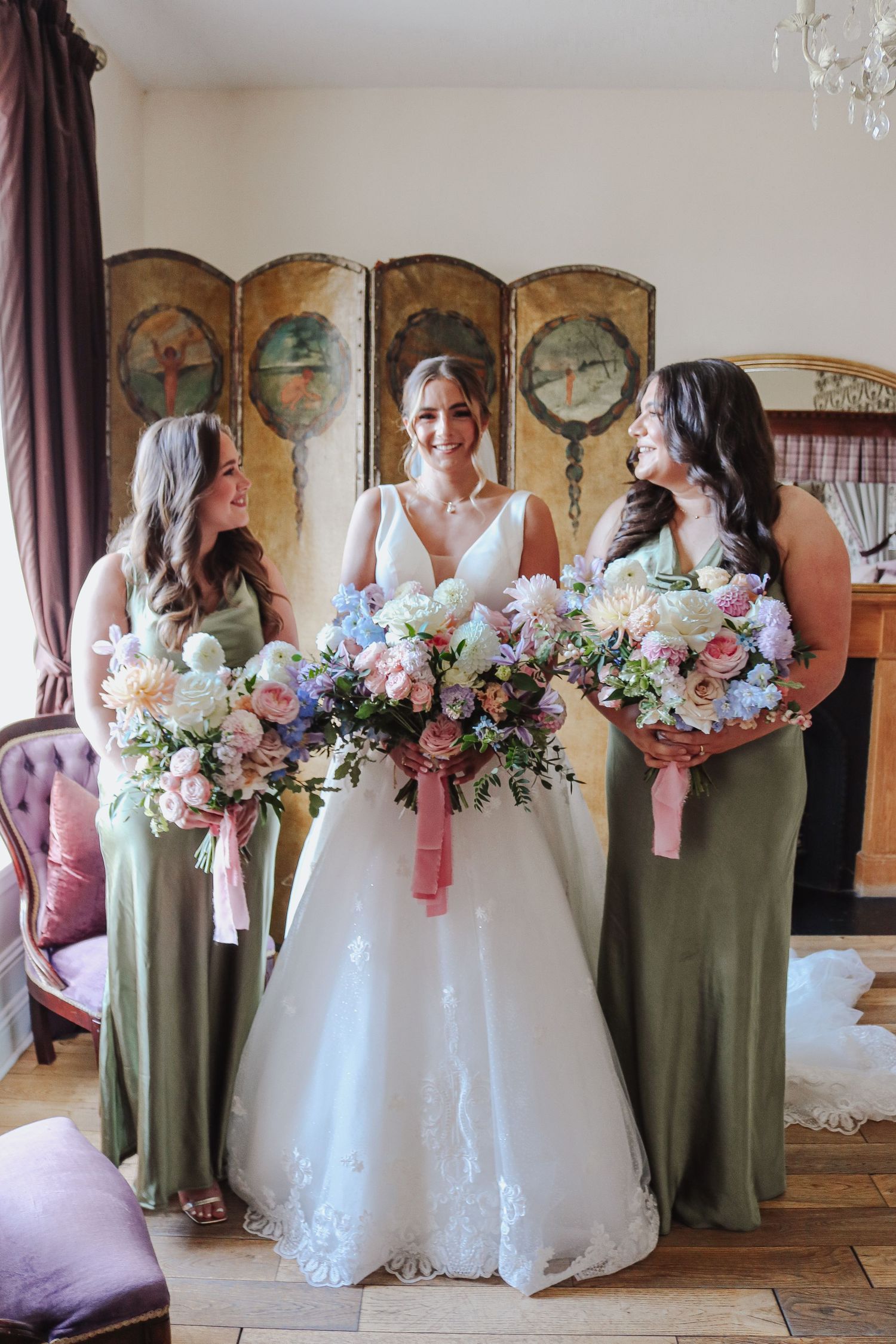 Wedding party in olive green bridesmaid dresses and white bridal gown holding pink and white floral bouquets.