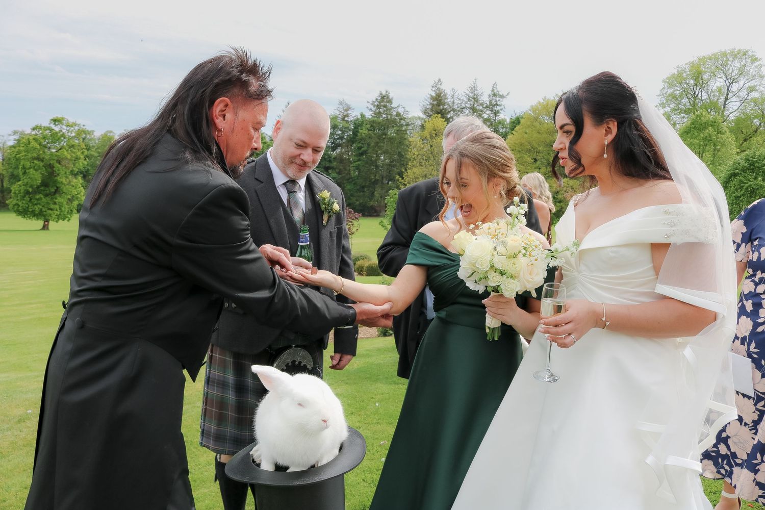 Outdoor wedding ceremony with bride, groom, officiant, and guests petting a white rabbit on a golf course.