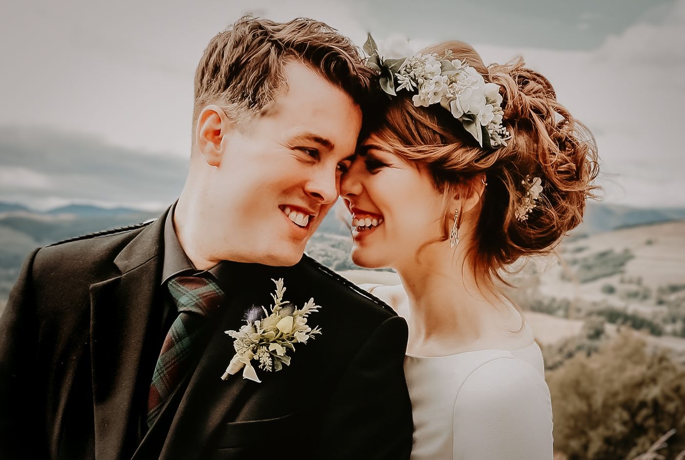 Couple in wedding attire sharing intimate moments against Aberdeenshire scenic backdrop during golden hour sunset.