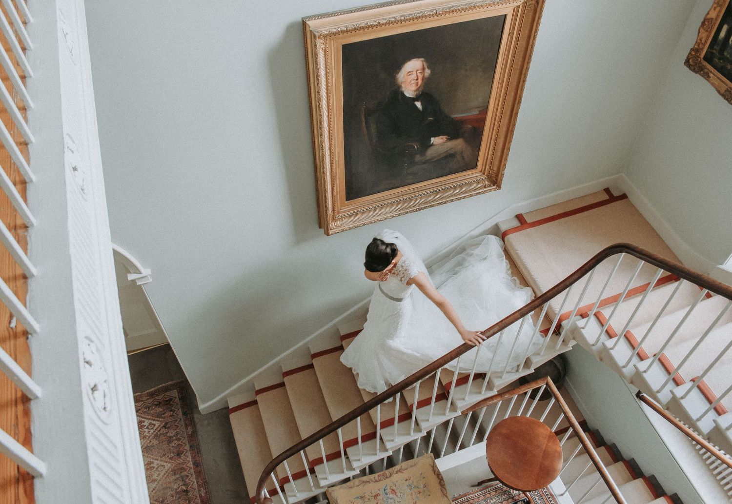 Looking down a curved staircase with white railings and beige carpeting in an elegant home interior.