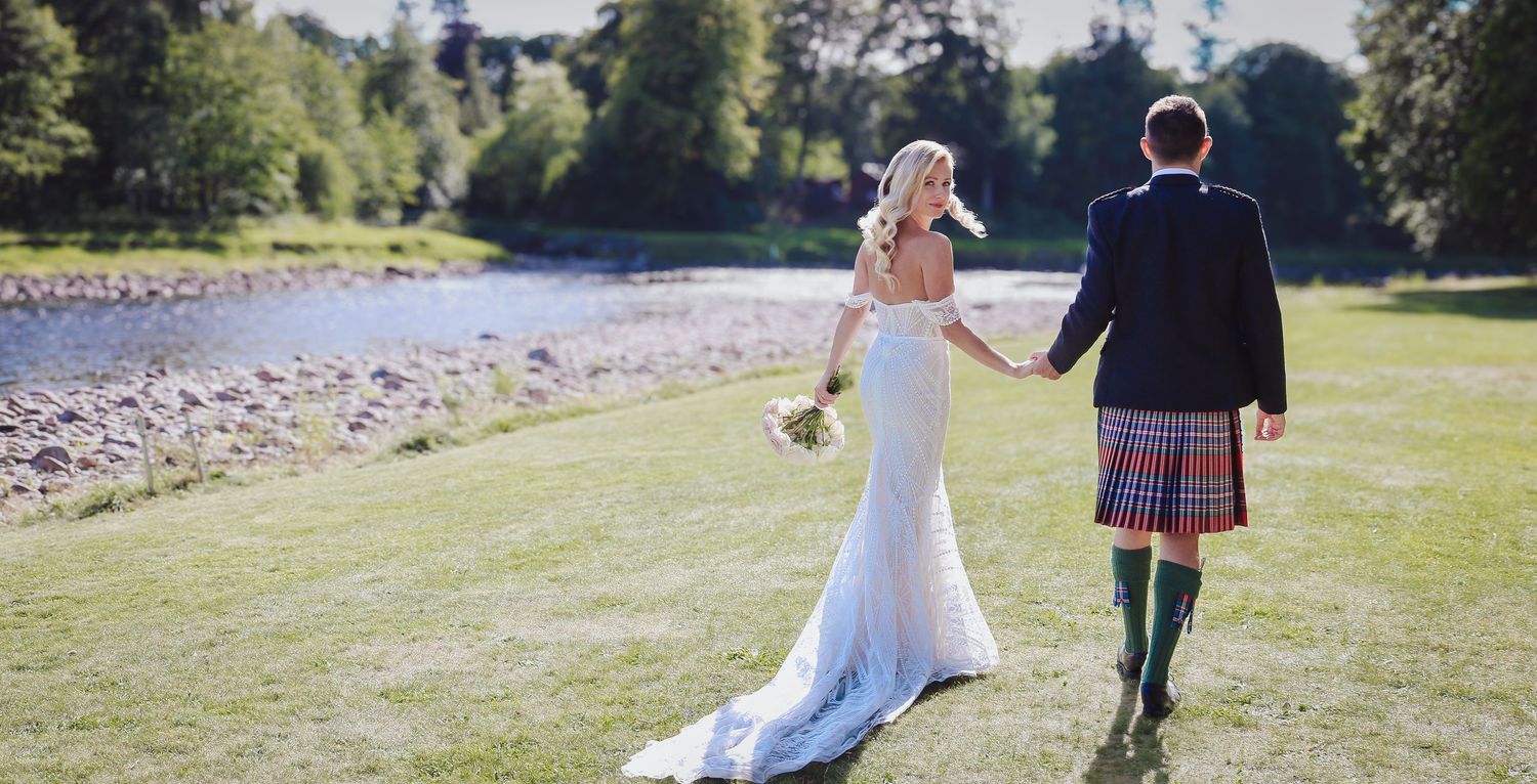 Wedding couple walks hand in hand through lush garden setting on their special day.