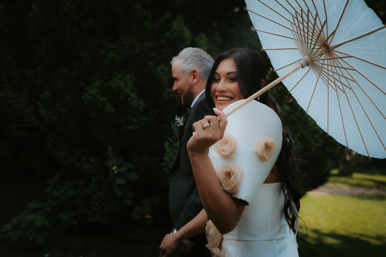 Romantic couple shares intimate moments under white parasols during an outdoor wedding photoshoot.