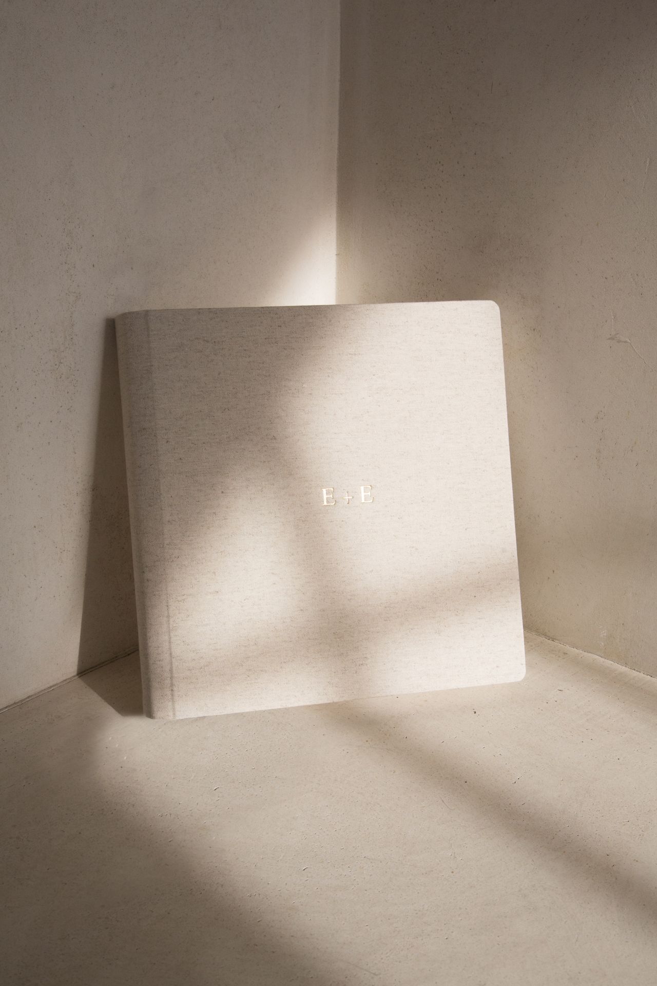 A minimalist white canvas or board leaning against a corner wall, casting subtle shadows in soft lighting.