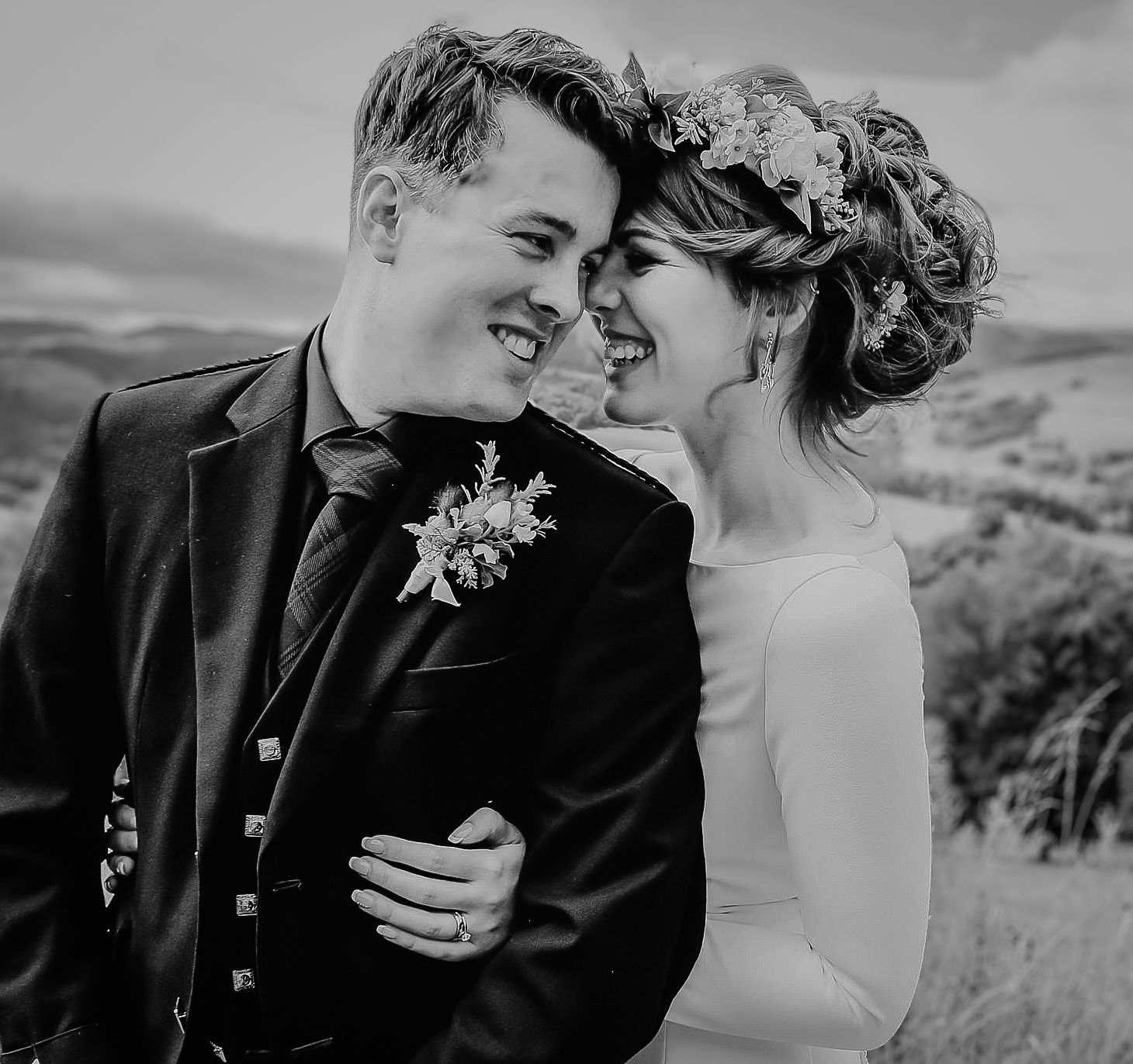 A romantic black and white wedding photo showing a joyful couple sharing an intimate moment in a scenic outdoor setting.