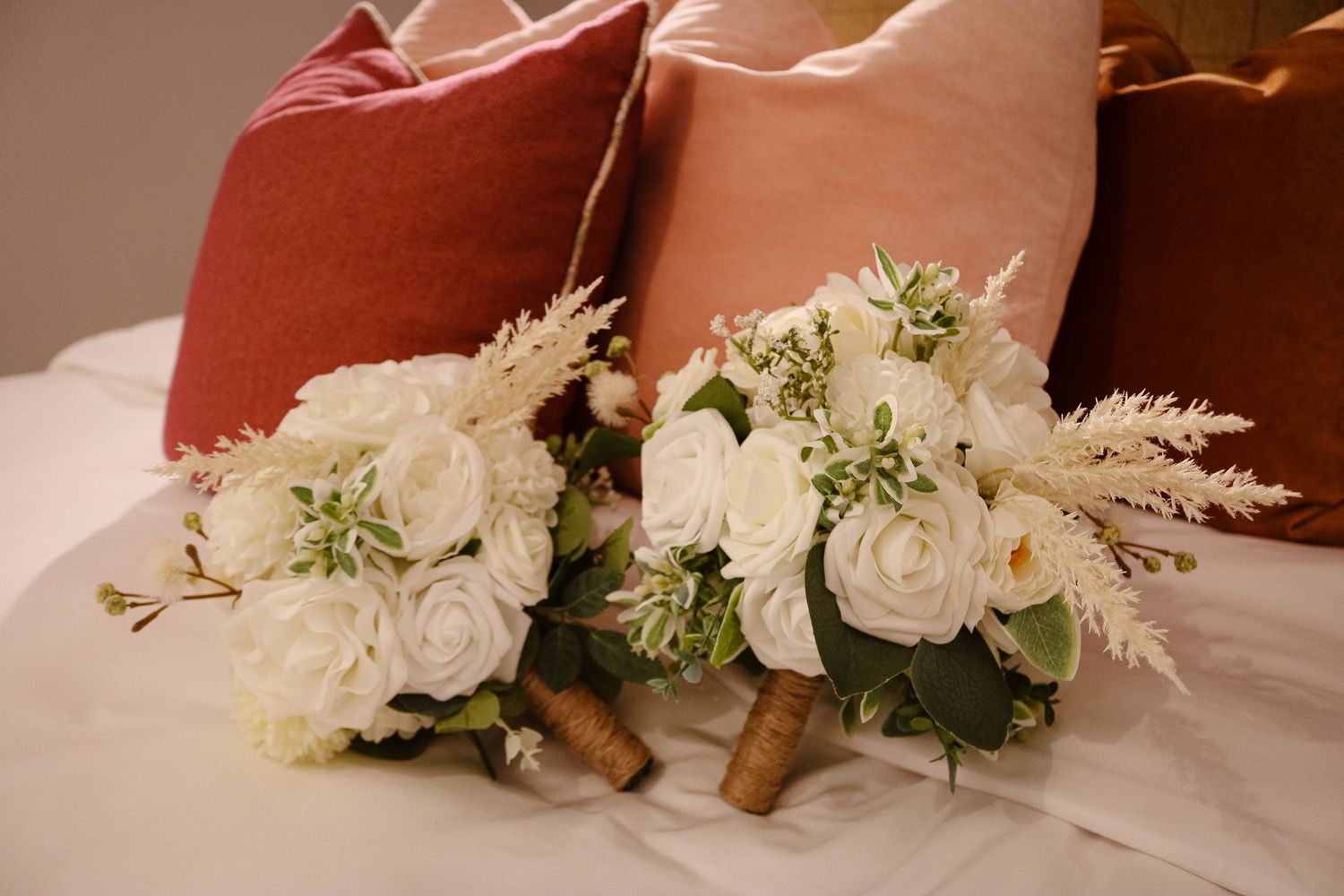 A delicate white floral bouquet with roses and pampas grass arranged for a wedding celebration.
