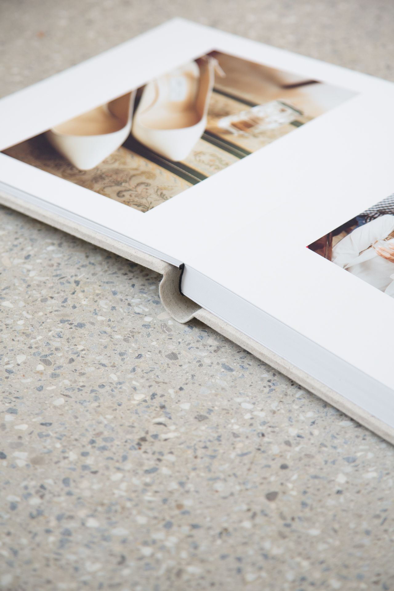 Close-up view of white photo album pages against a textured concrete surface showing minimalist layout design.