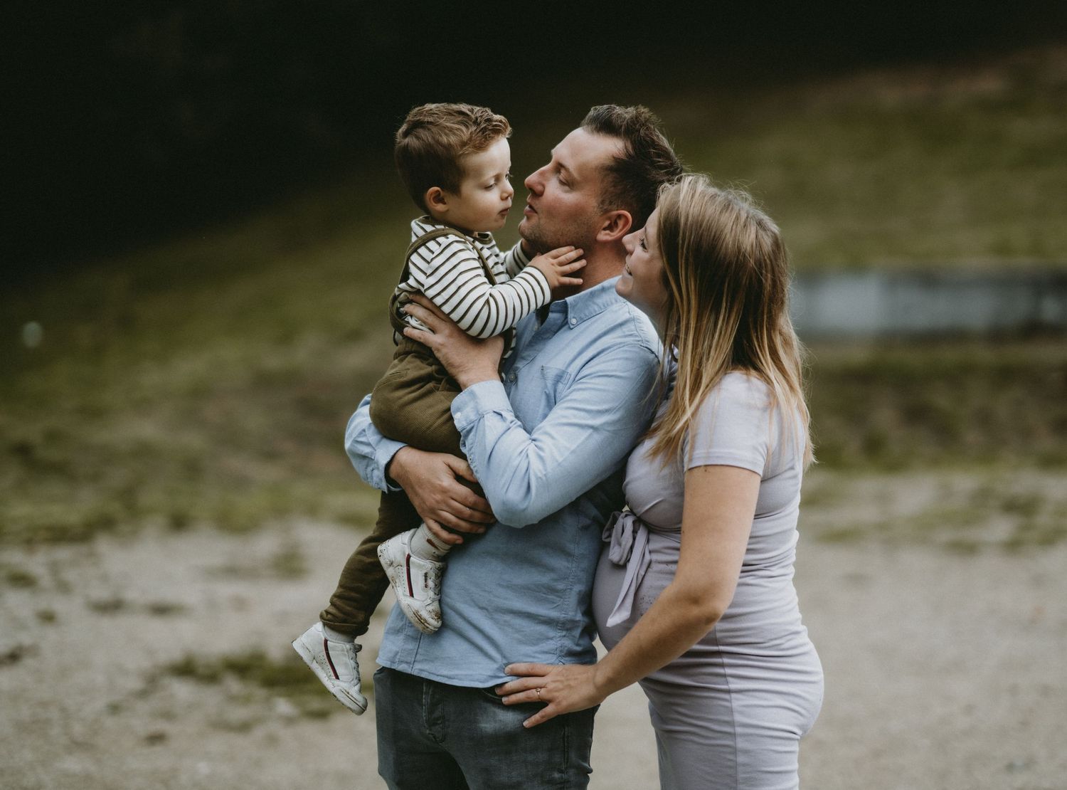 Family enjoying tender moments together outdoors in a natural setting during a photo session.