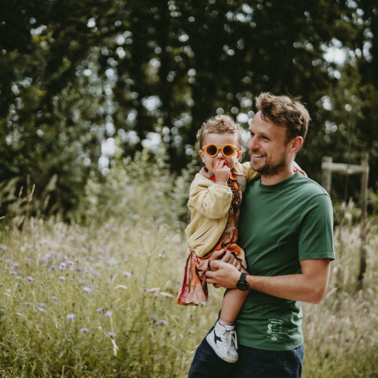 A parent and child share tender moments together in a wildflower meadow.