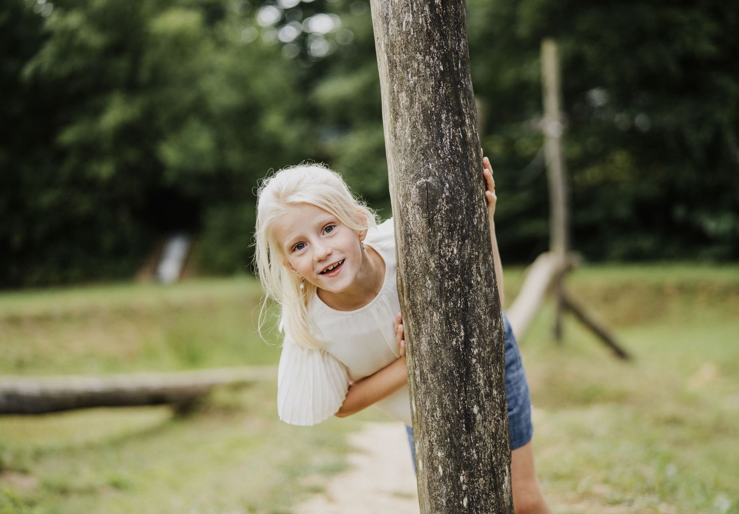 Playful moments captured around a tree trunk during an outdoor family photoshoot.