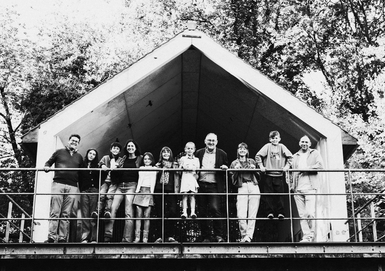 Black and white panorama of wedding guests lined up on a balcony with white architectural details.