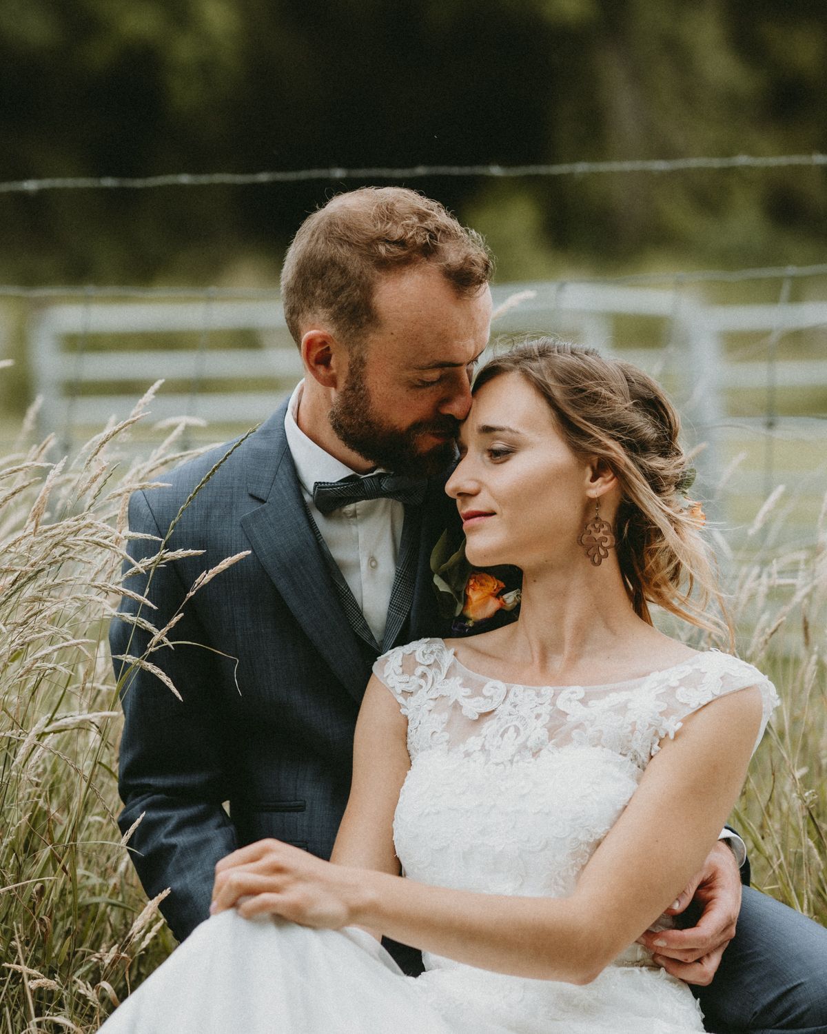 Couple shares tender moments in a field of tall grass during their wedding photoshoot.