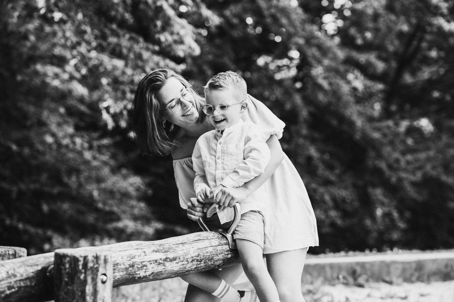Black and white family portraits captured on a rustic wooden bench outdoors.