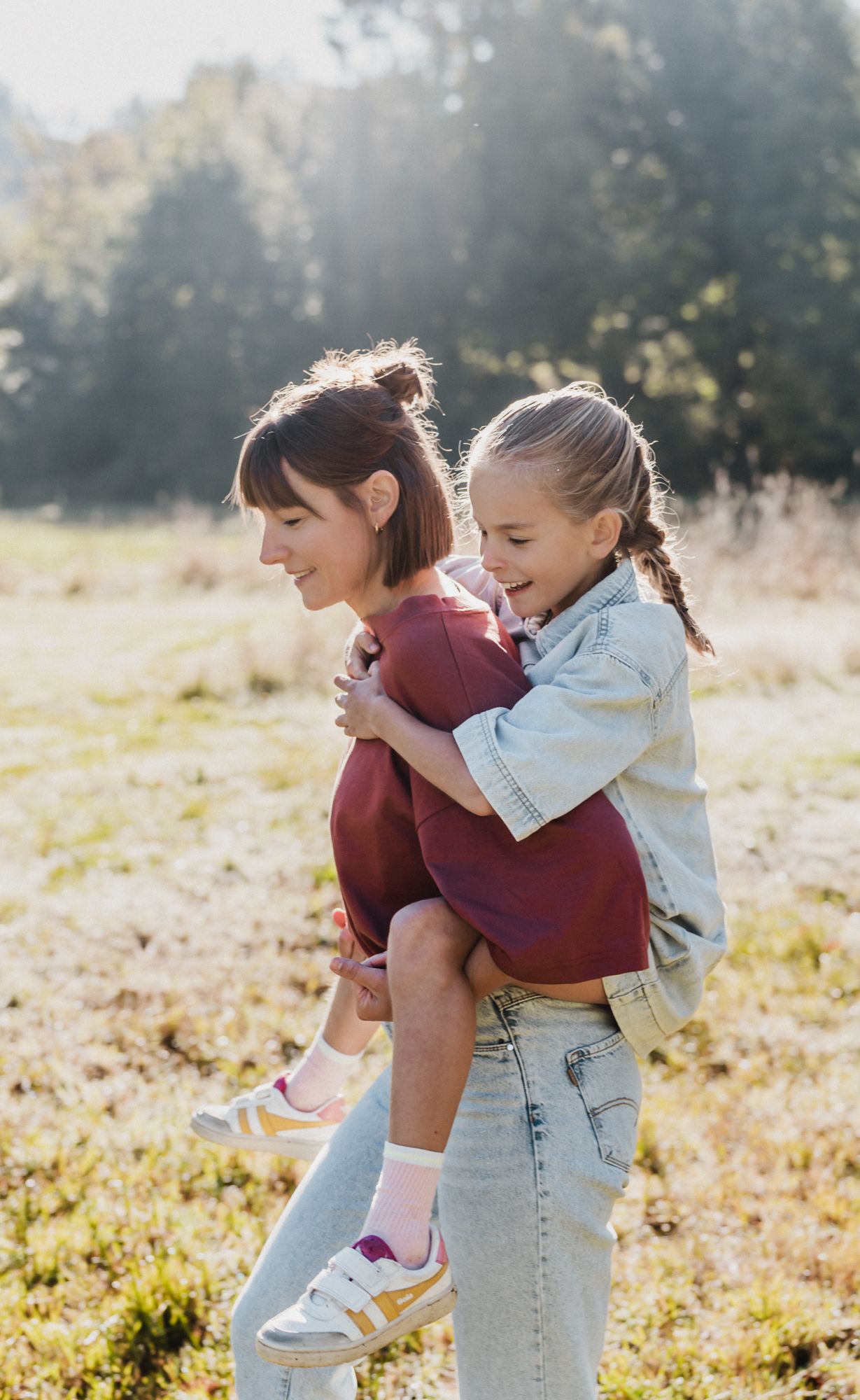 Mother and child playing together in a sunlit meadow during golden hour.