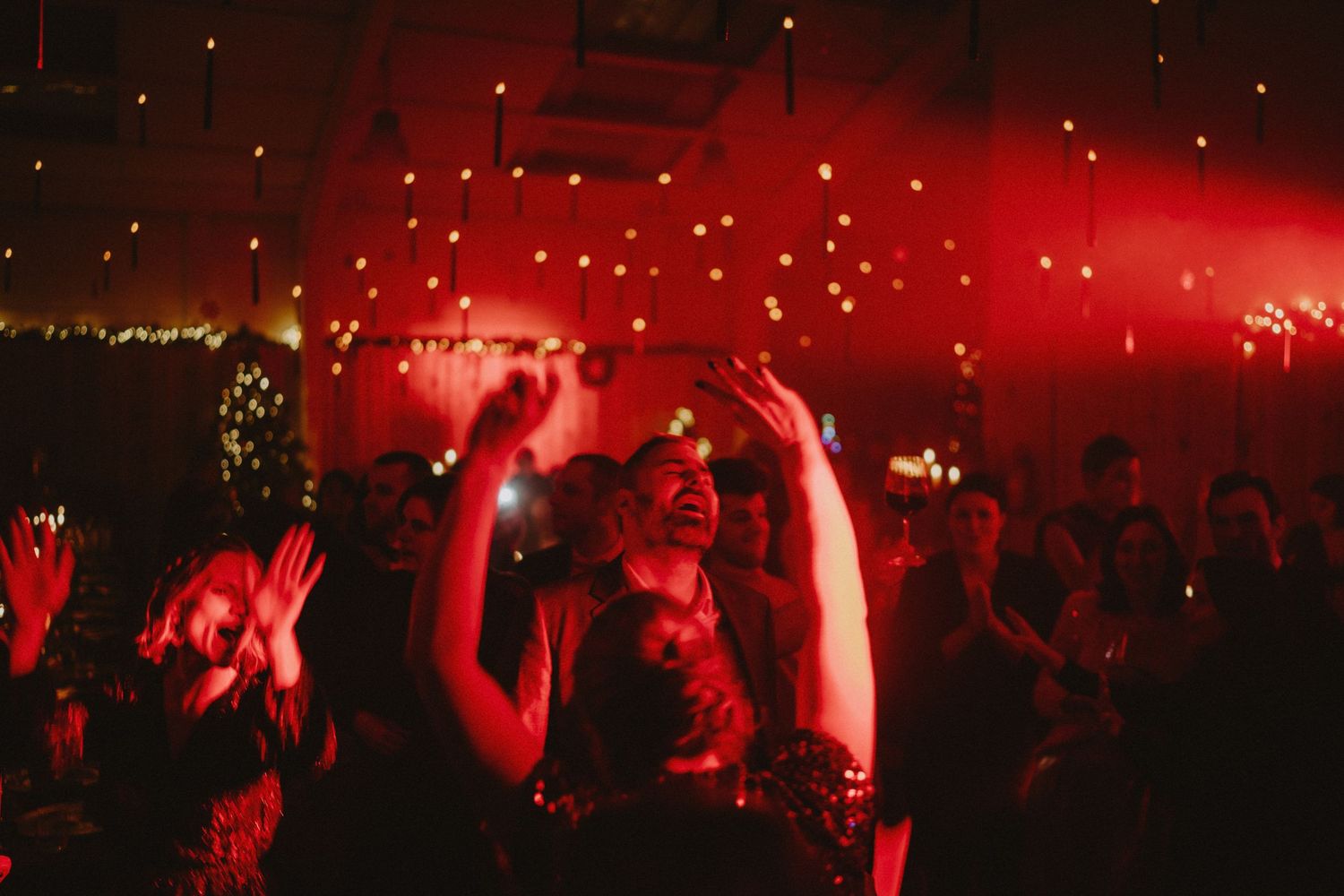 Concert crowd silhouetted against dramatic red lighting and stage effects.