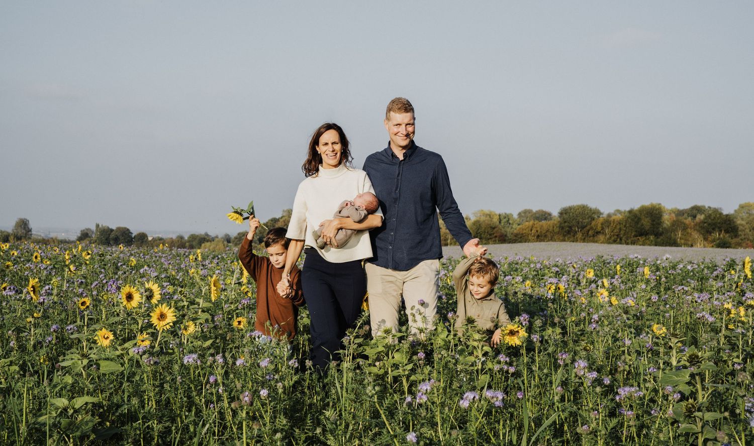 Family walking through a sunflower field during golden hour.