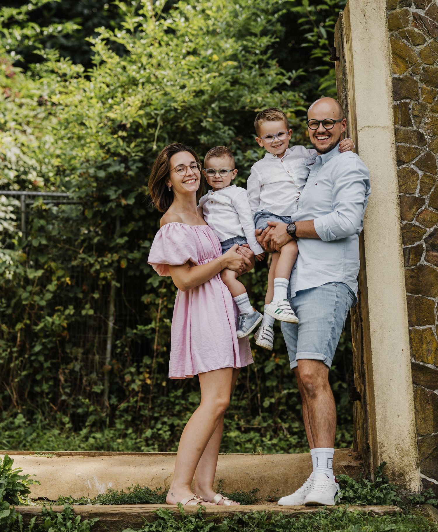 Family sharing joyful moments together under stone pillars in a garden setting.
