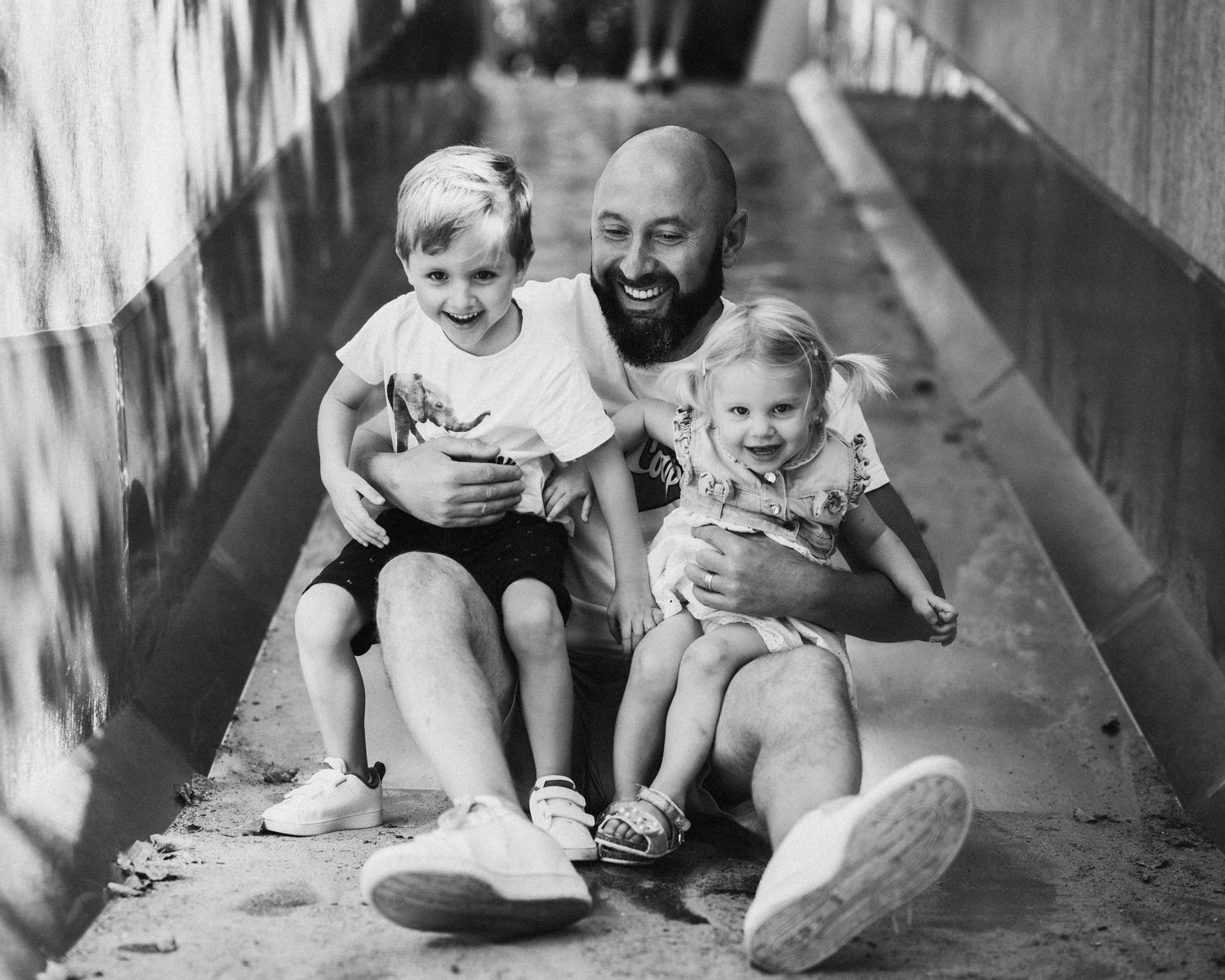 Black and white photo series showing playful moments under a concrete structure.