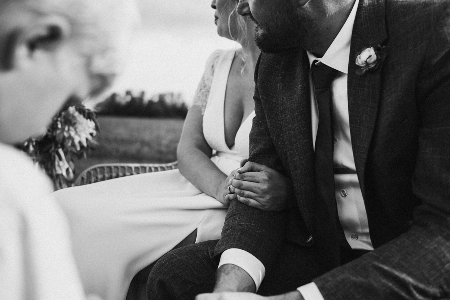 Black and white photo of bride and groom holding hands during intimate wedding ceremony moment.
