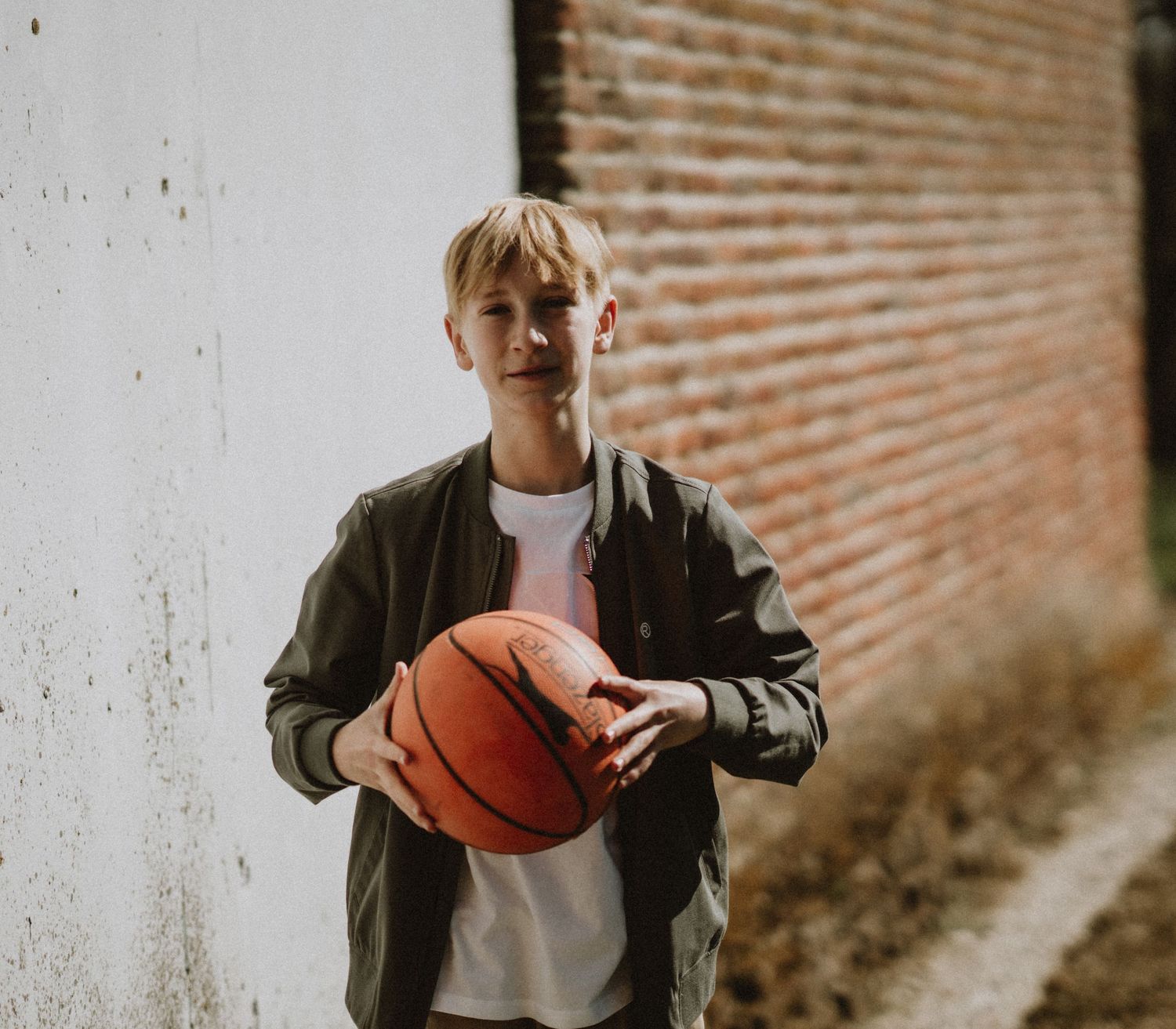 A stylish casual portrait against a brick wall with dramatic shadows.