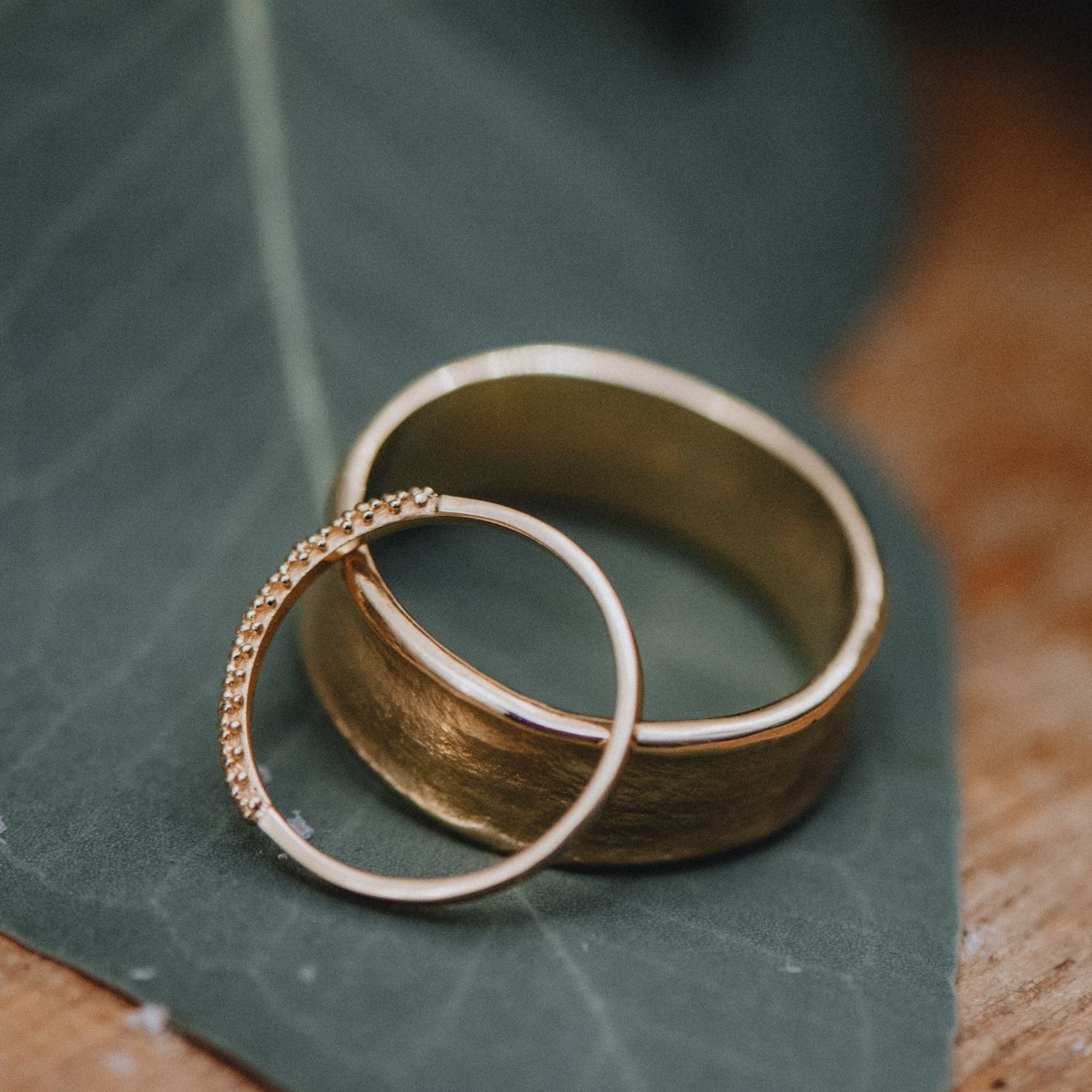 Close-up detail of wedding rings on a dark textured surface.